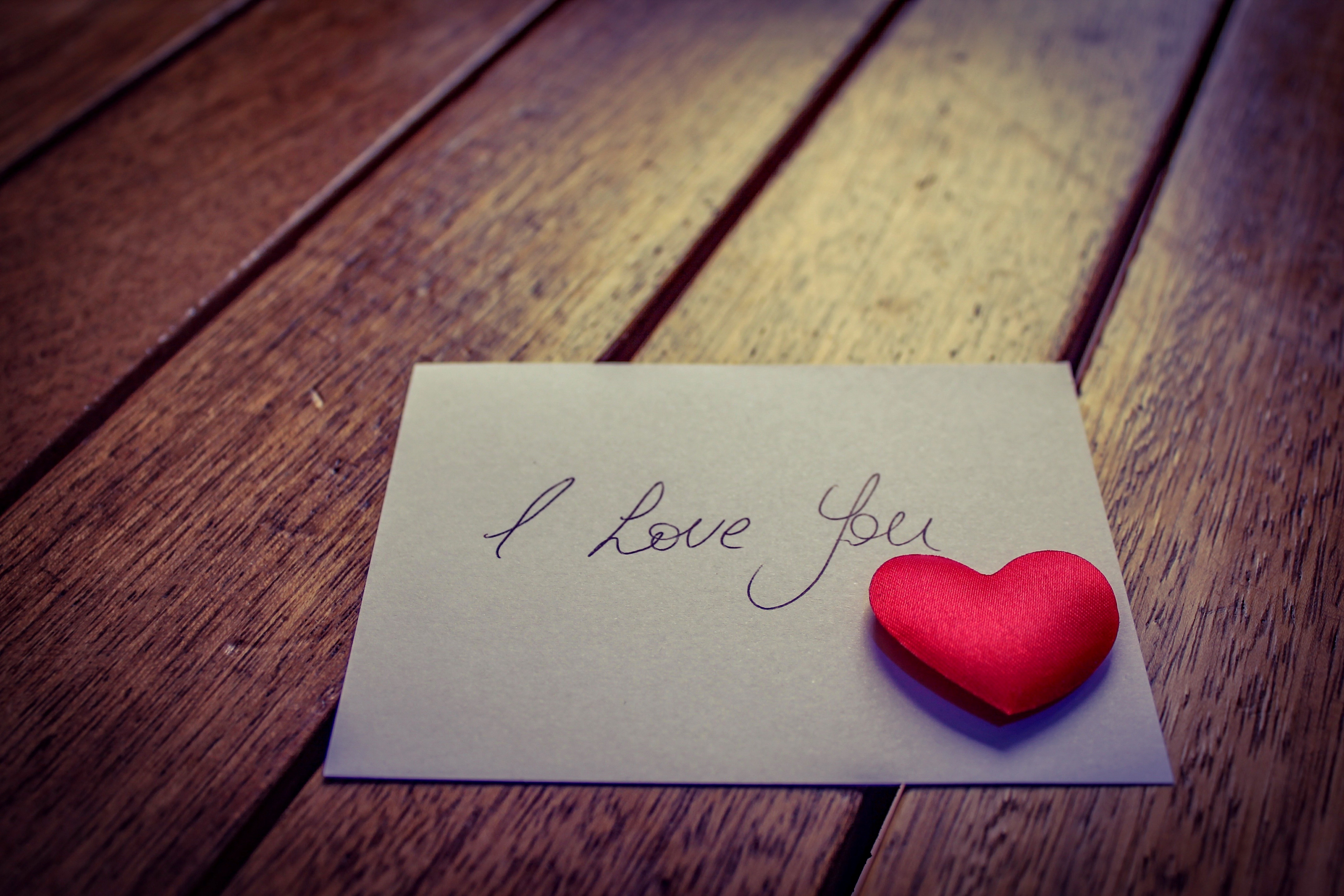 Card with "I love you" and red heart on wooden table HD Wallpaper