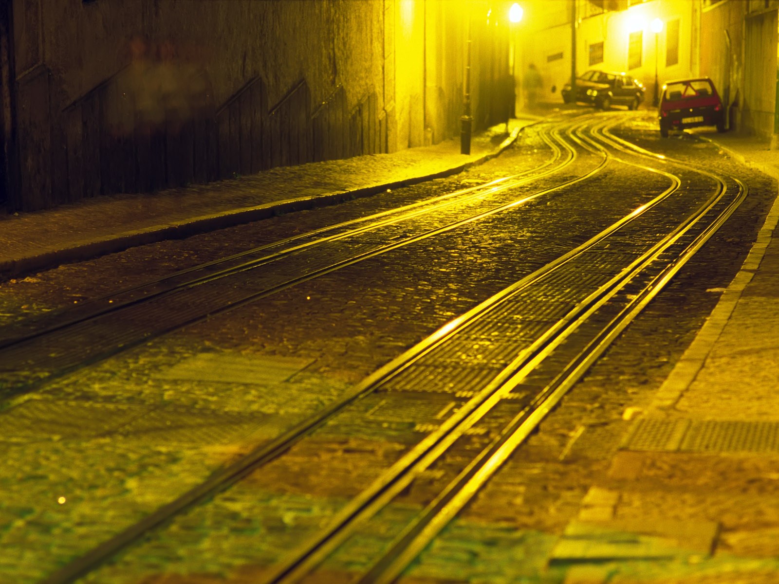 Tram tracks on a cobblestone street at night HD Wallpaper