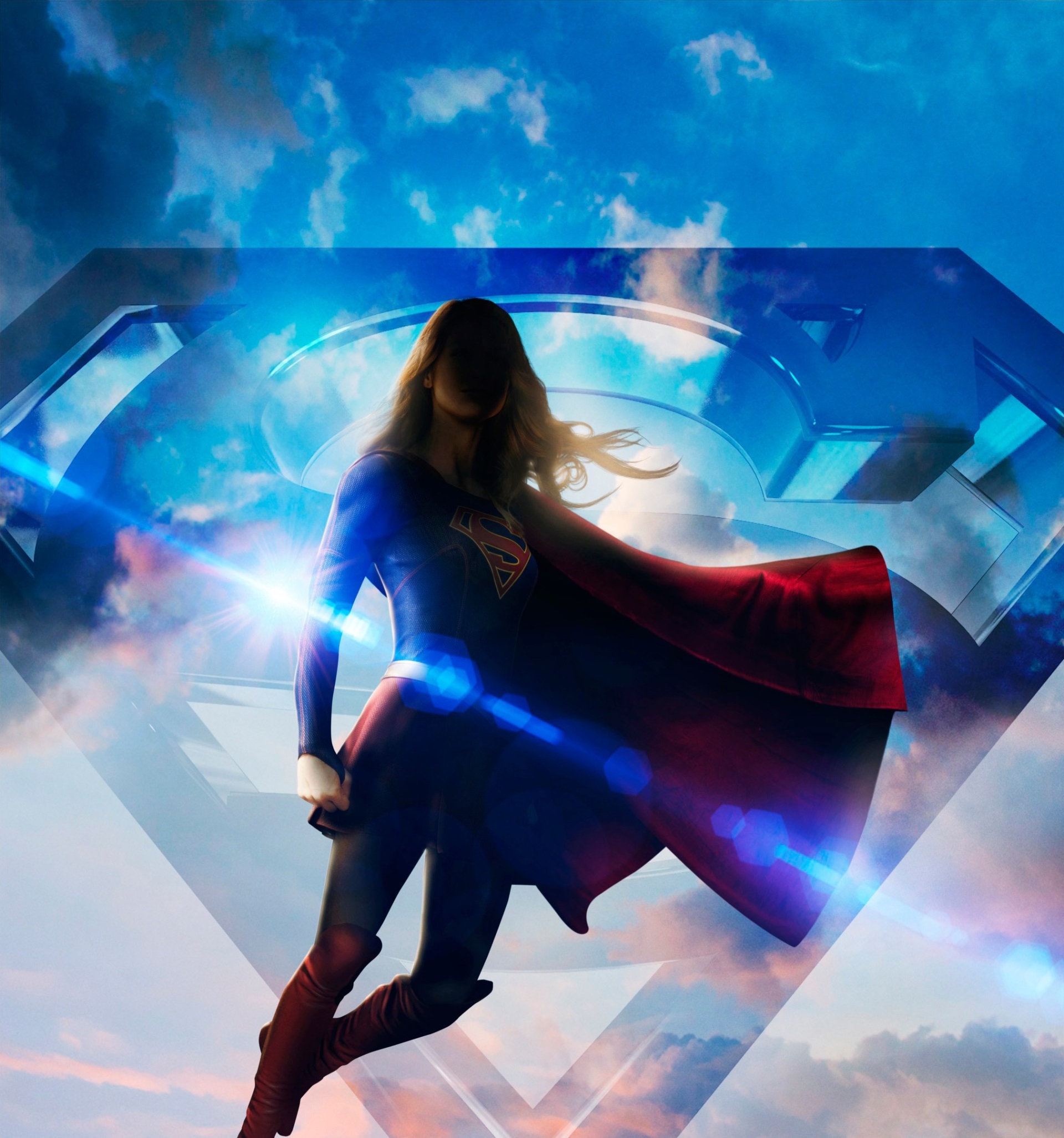 Supergirl flying in front of a large S shield HD Wallpaper