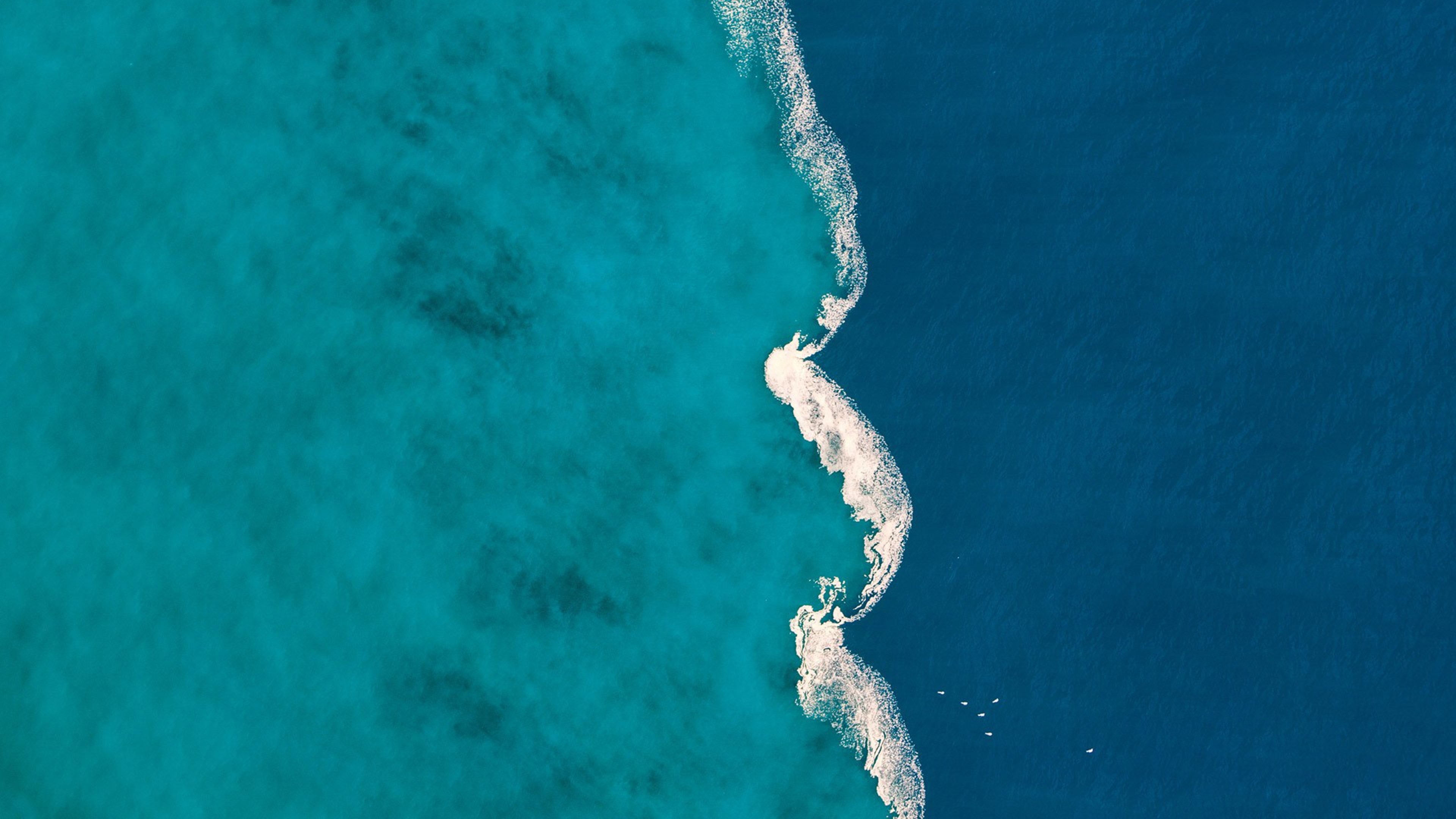 Aerial view of turquoise and deep blue ocean water with a wave HD Wallpaper