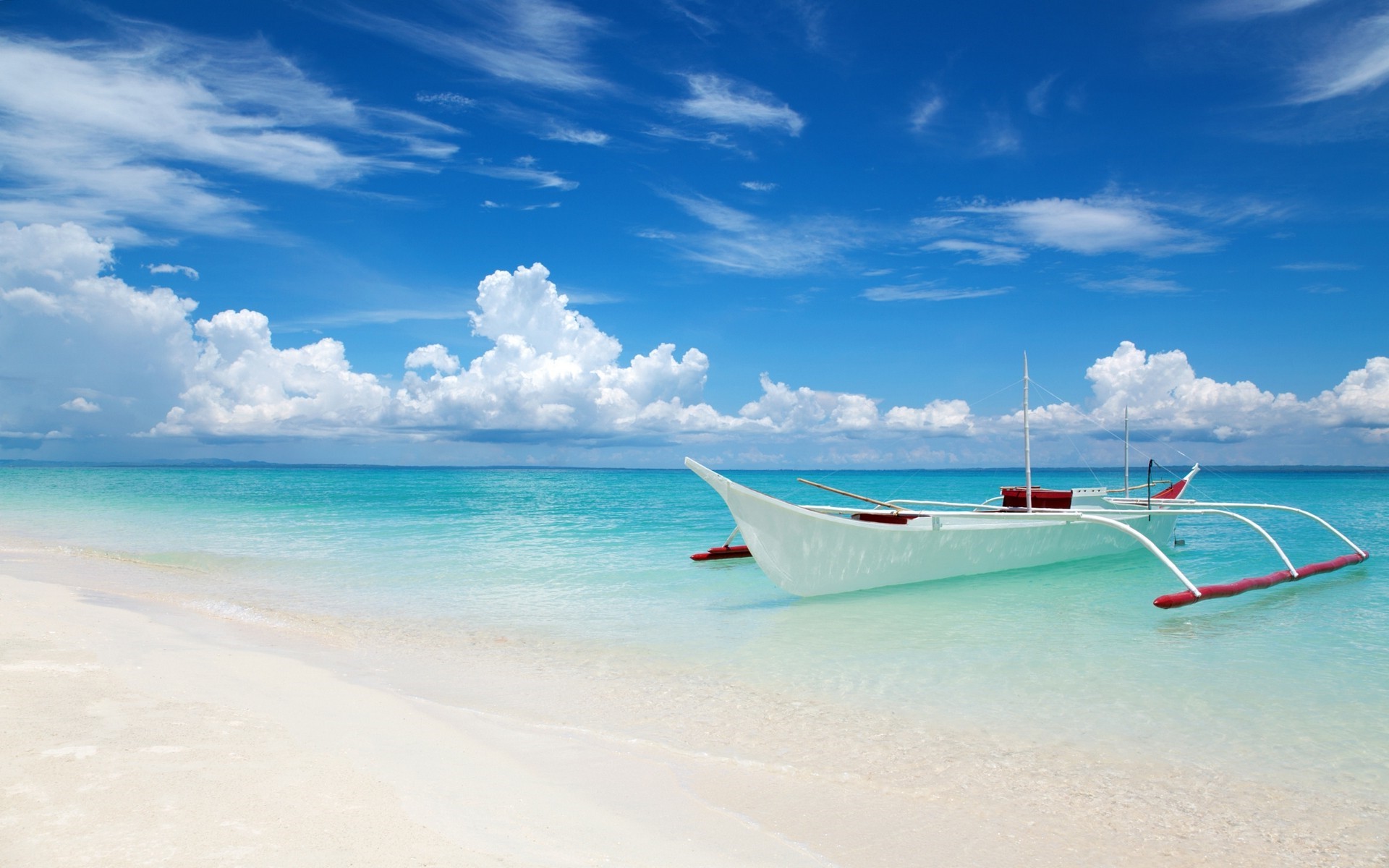 A traditional outrigger boat on a tropical beach HD Wallpaper