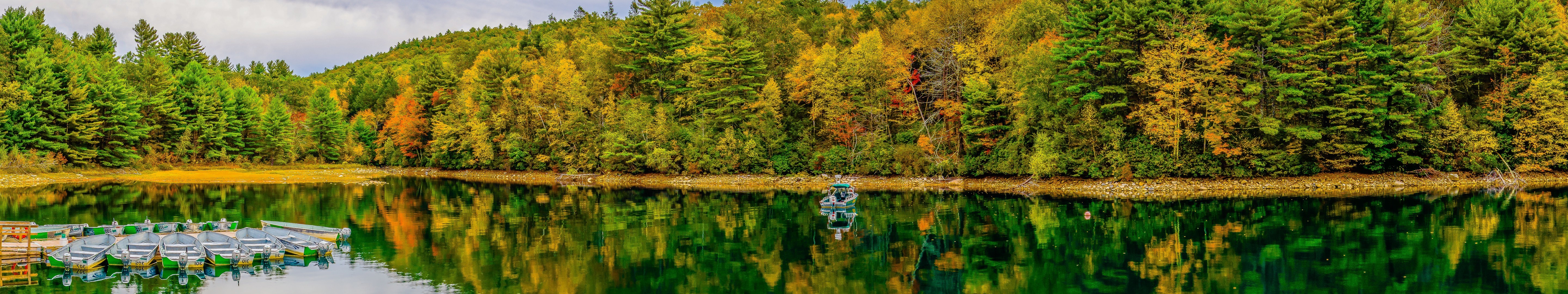 Autumn forest reflected in a calm lake with boats HD Wallpaper