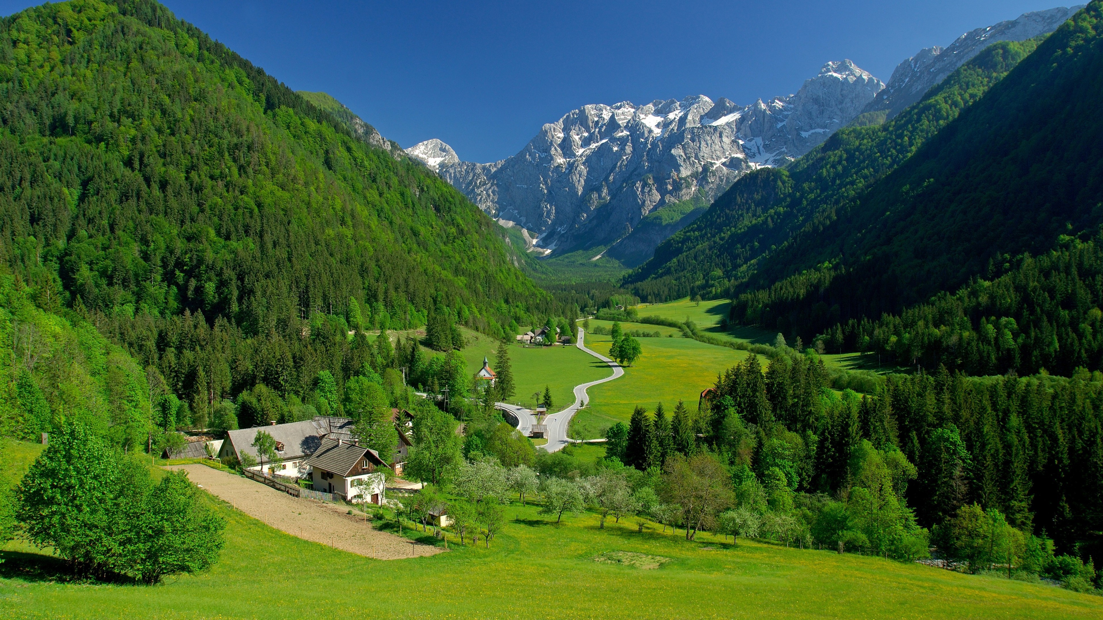 Scenic Alpine Valley with Village and Snowy Mountains in Slovenia HD Wallpaper