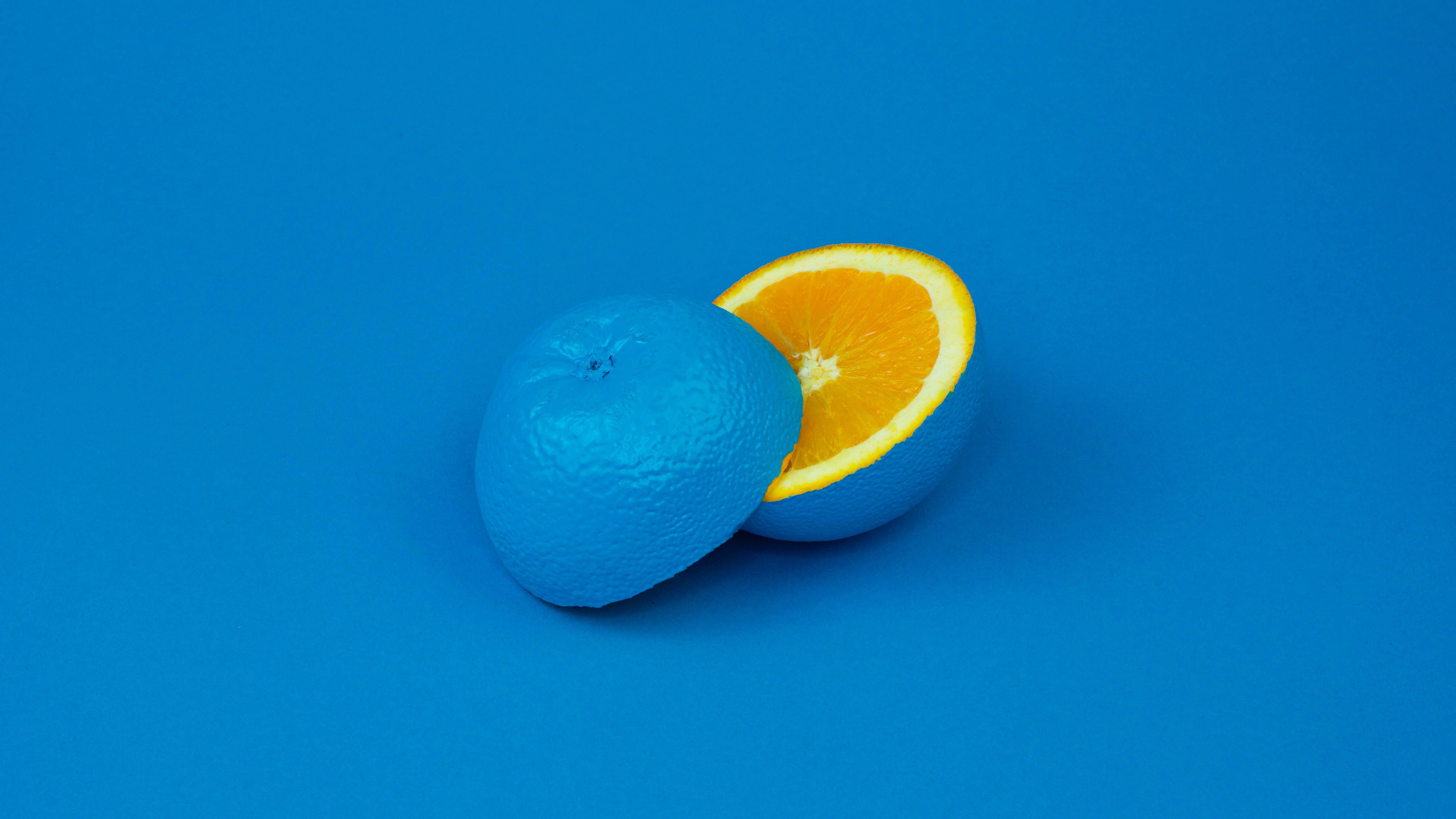 Blue painted orange cut in half on blue background HD Wallpaper