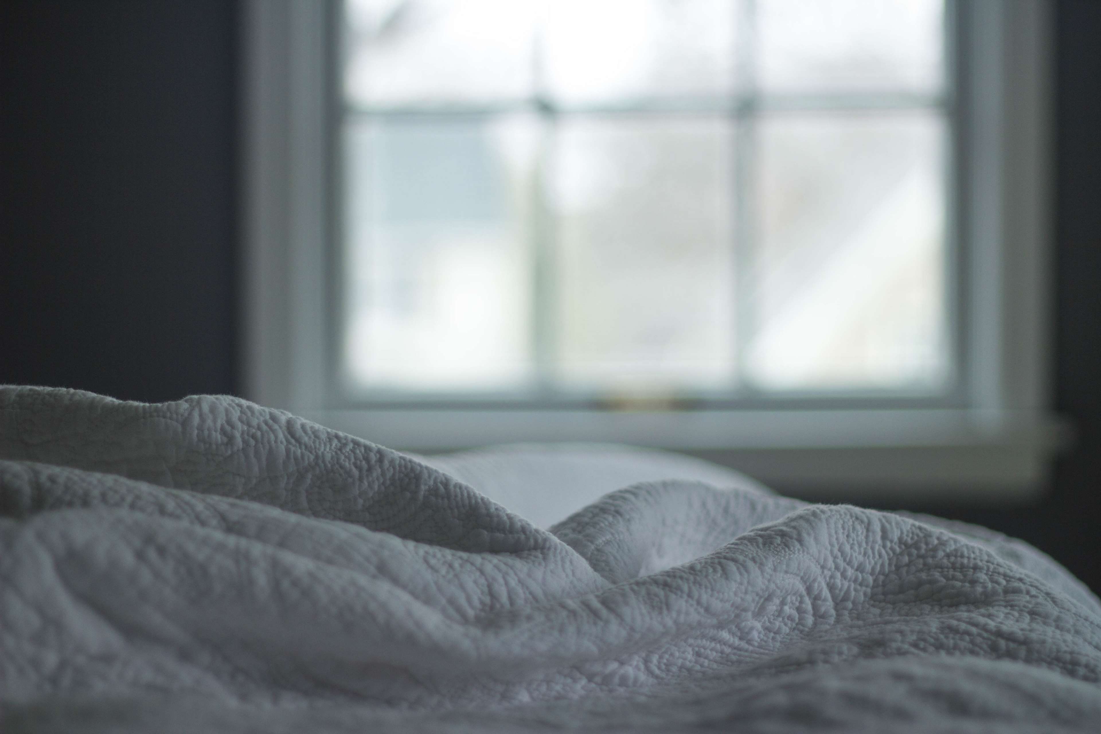 Textured blanket on a bed near a window HD Wallpaper