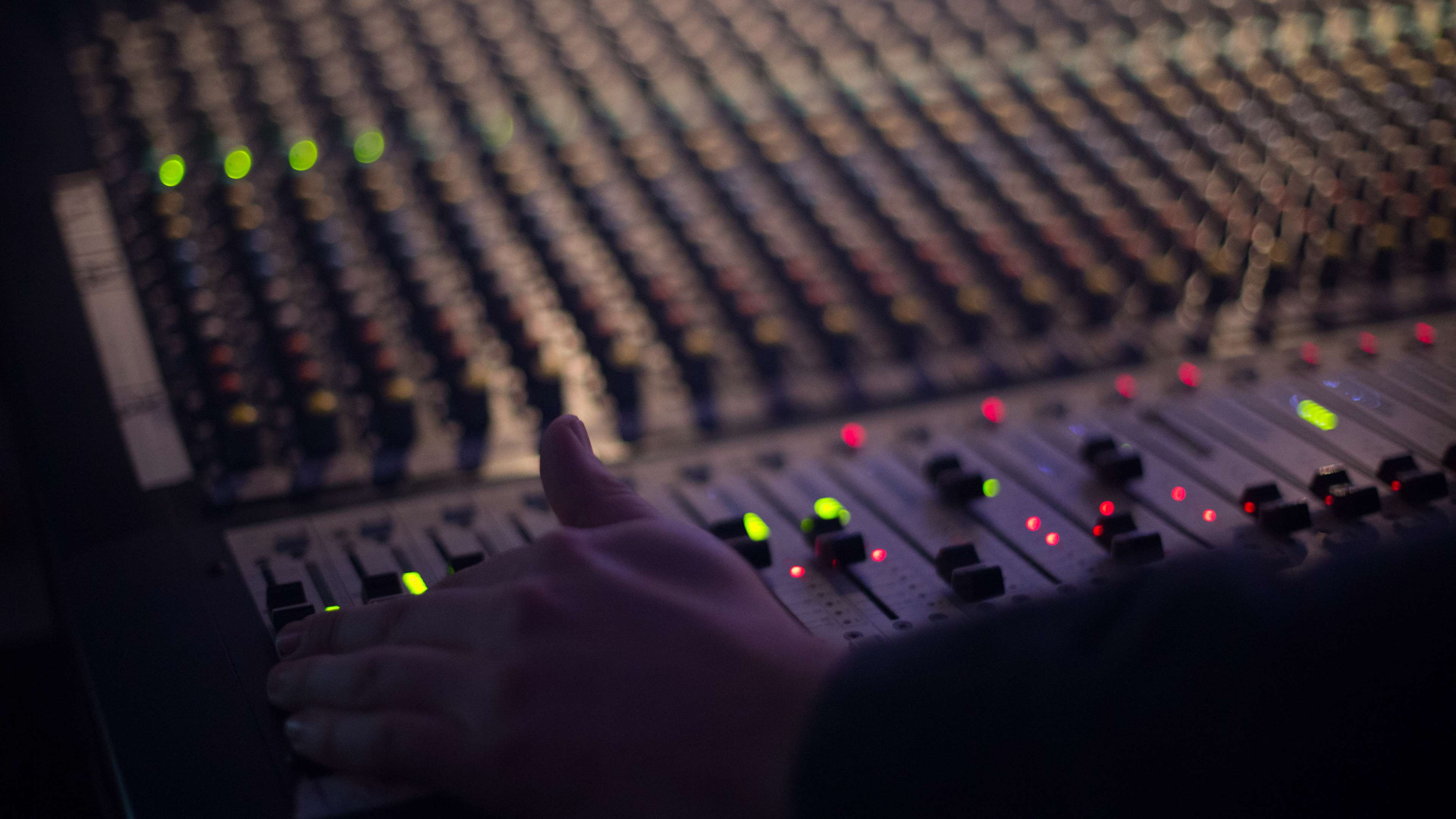 Hand on audio mixing console with lights HD Wallpaper