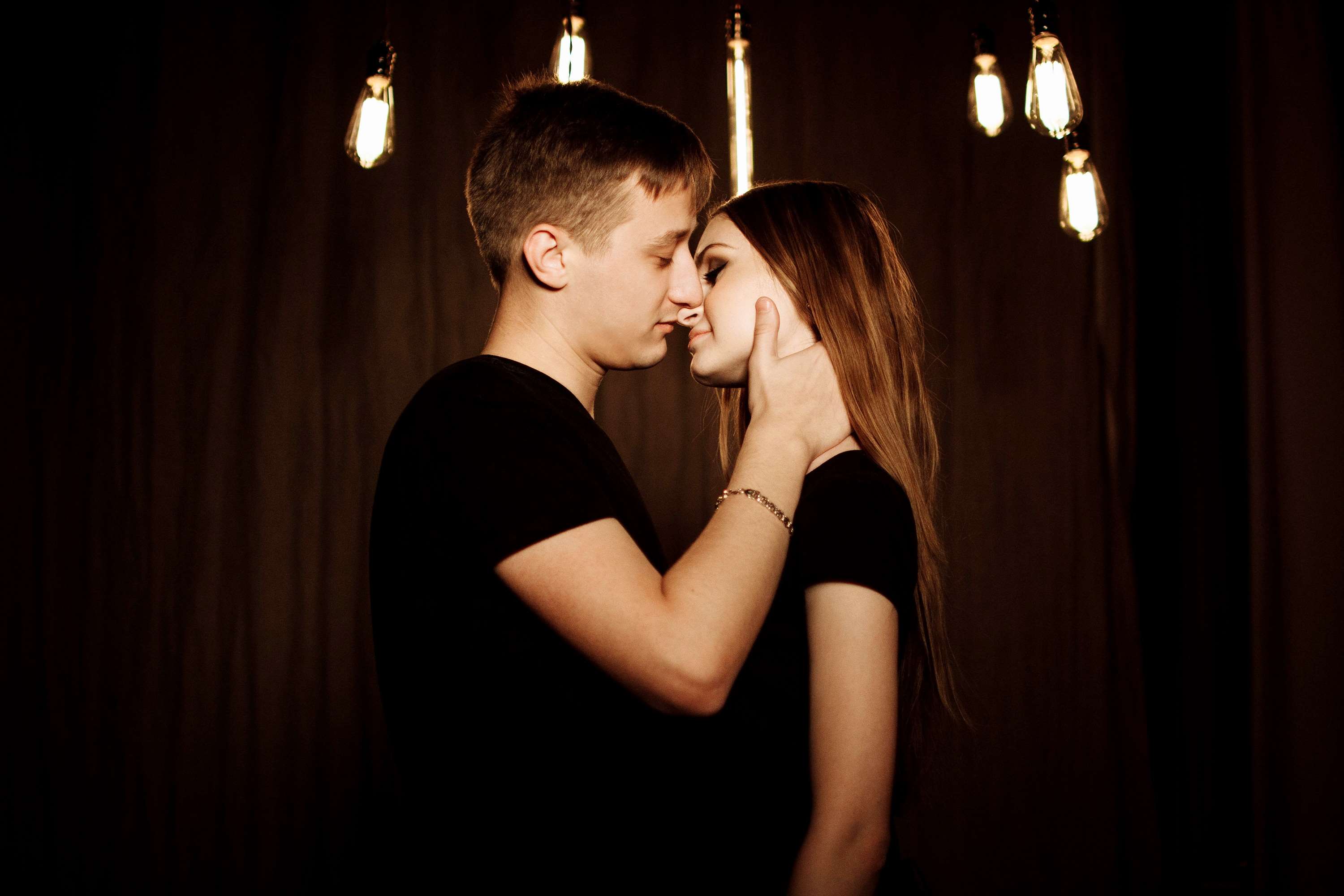 Couple kissing under Edison bulbs HD Wallpaper