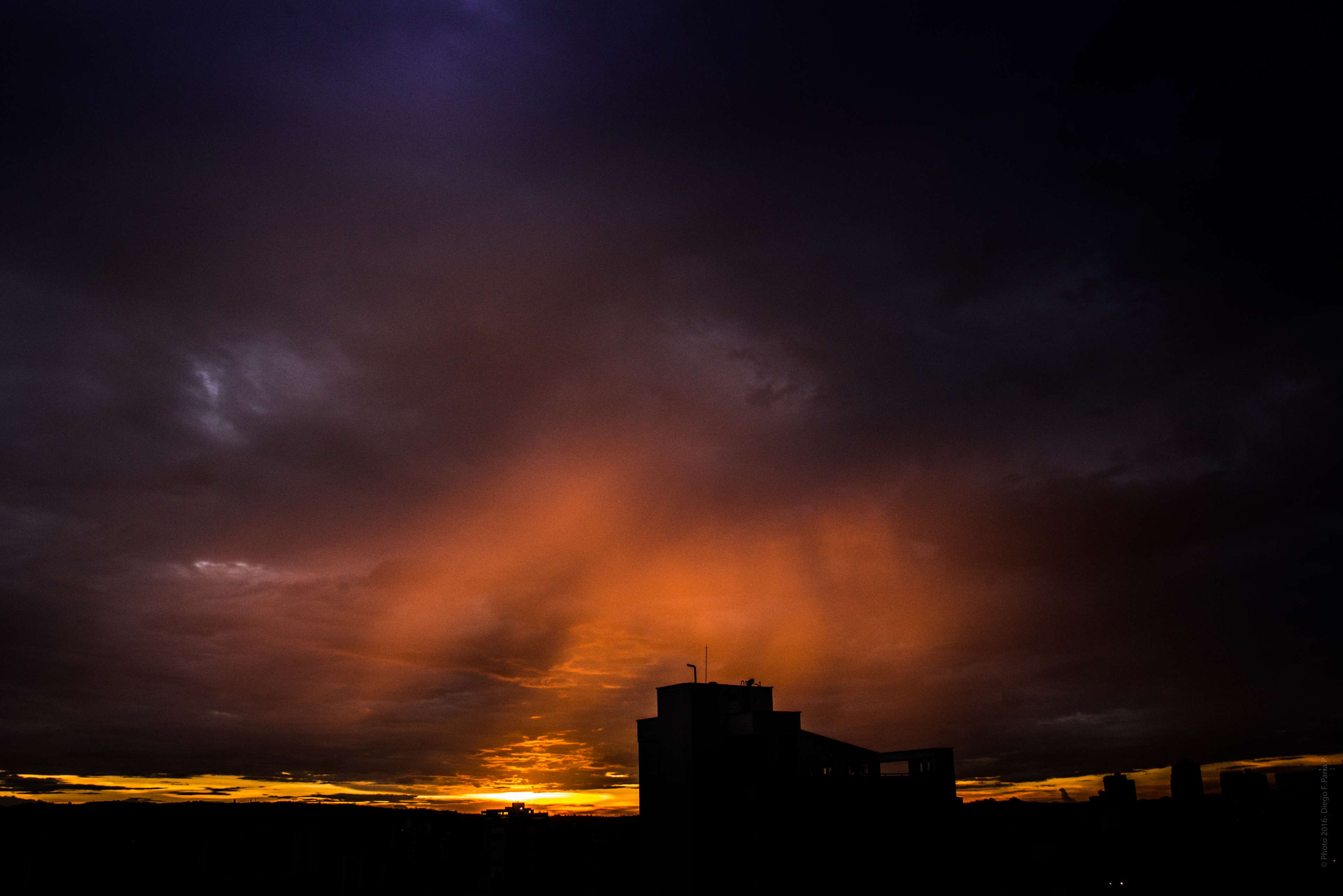 Sunset over city skyline with dramatic clouds HD Wallpaper