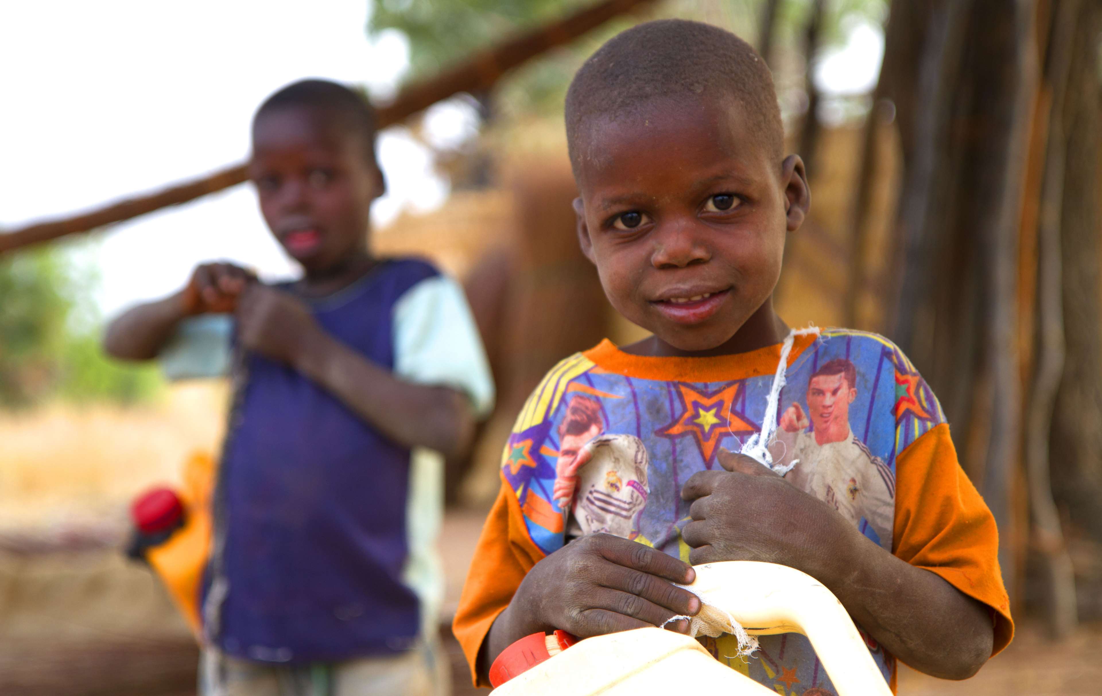 Two African children holding water containers in a village HD Wallpaper