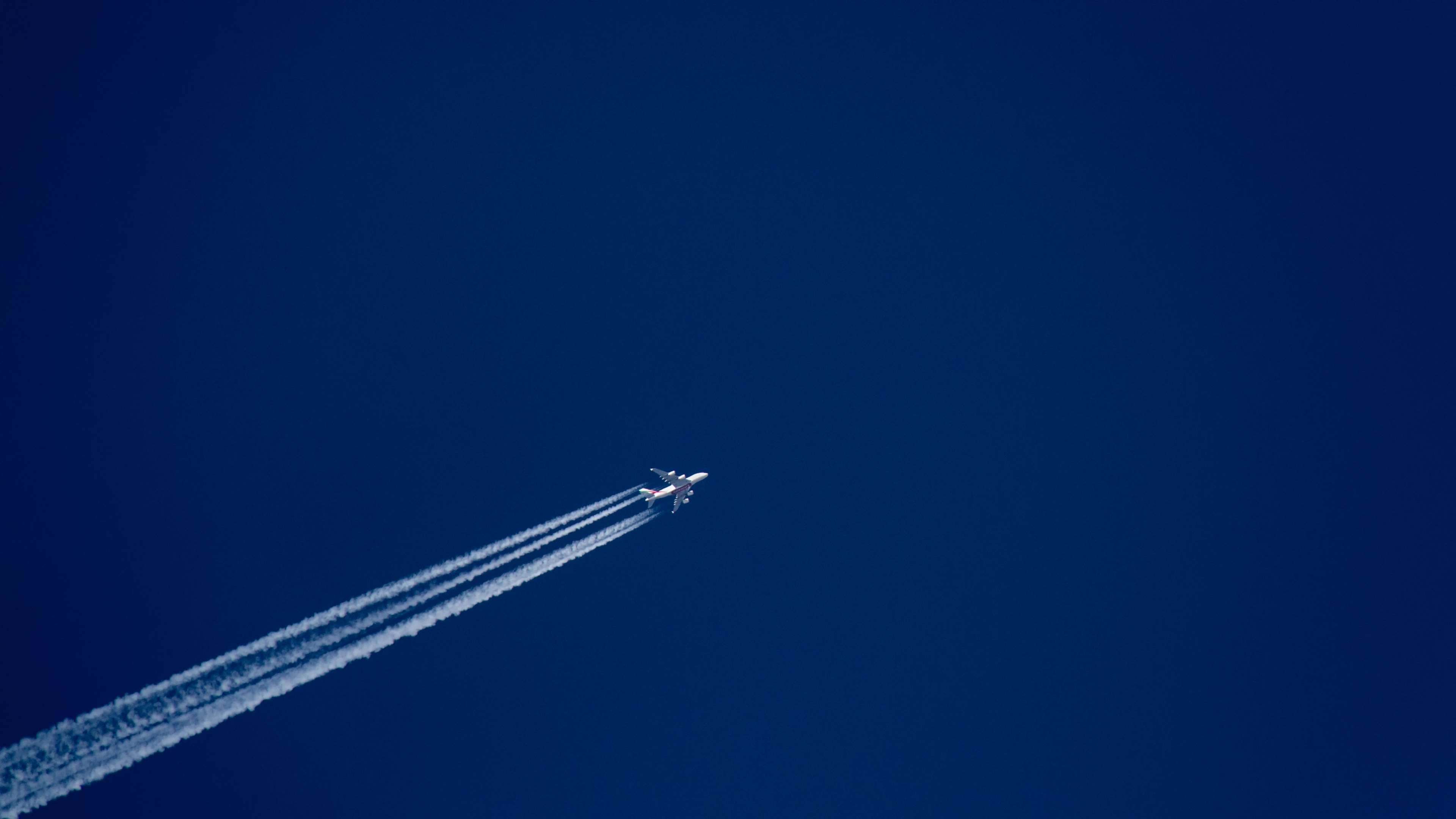 Airplane flying in a clear blue sky with contrails HD Wallpaper