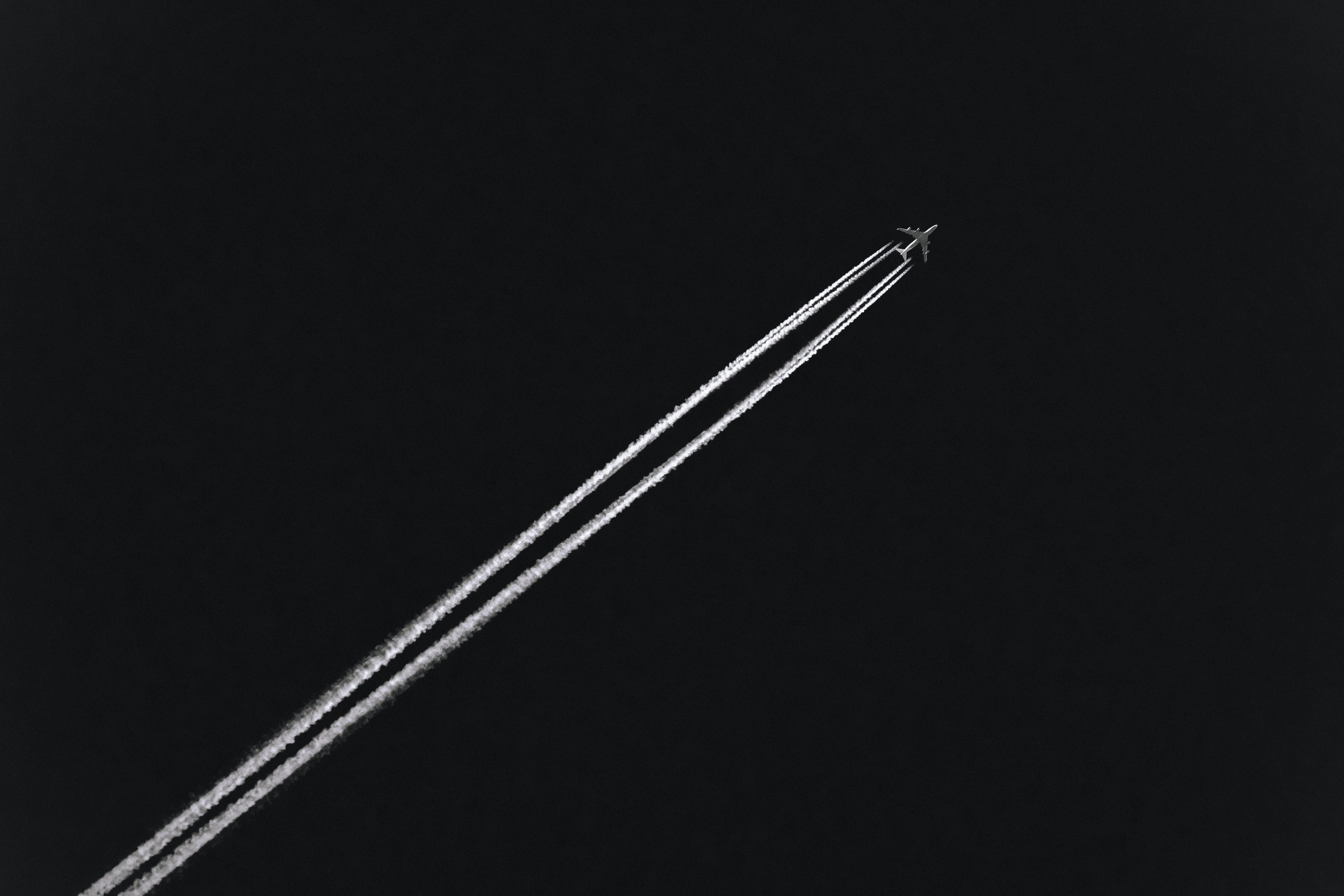Airplane leaving contrails in the dark sky HD Wallpaper