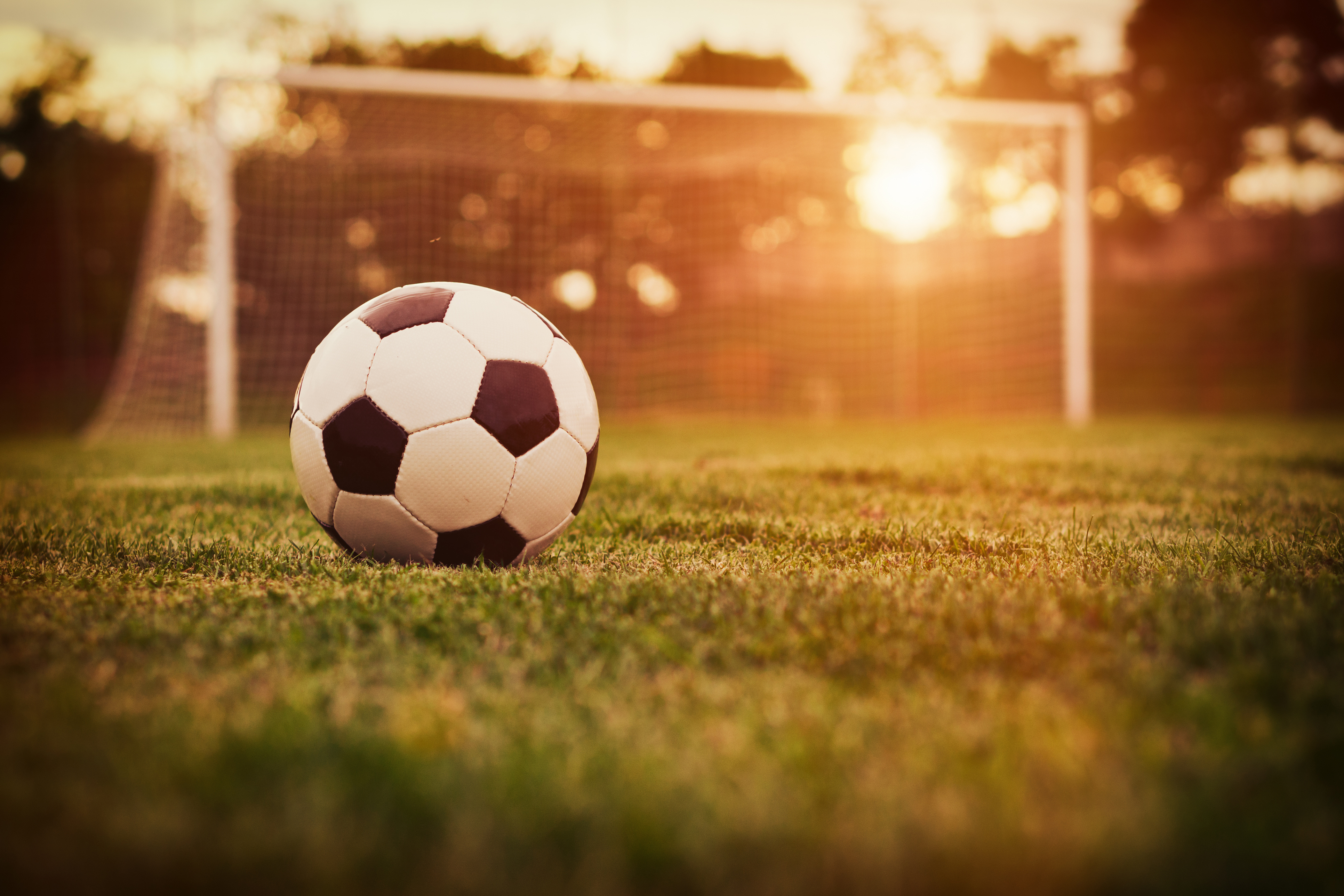 Soccer ball on a field at sunset HD Wallpaper