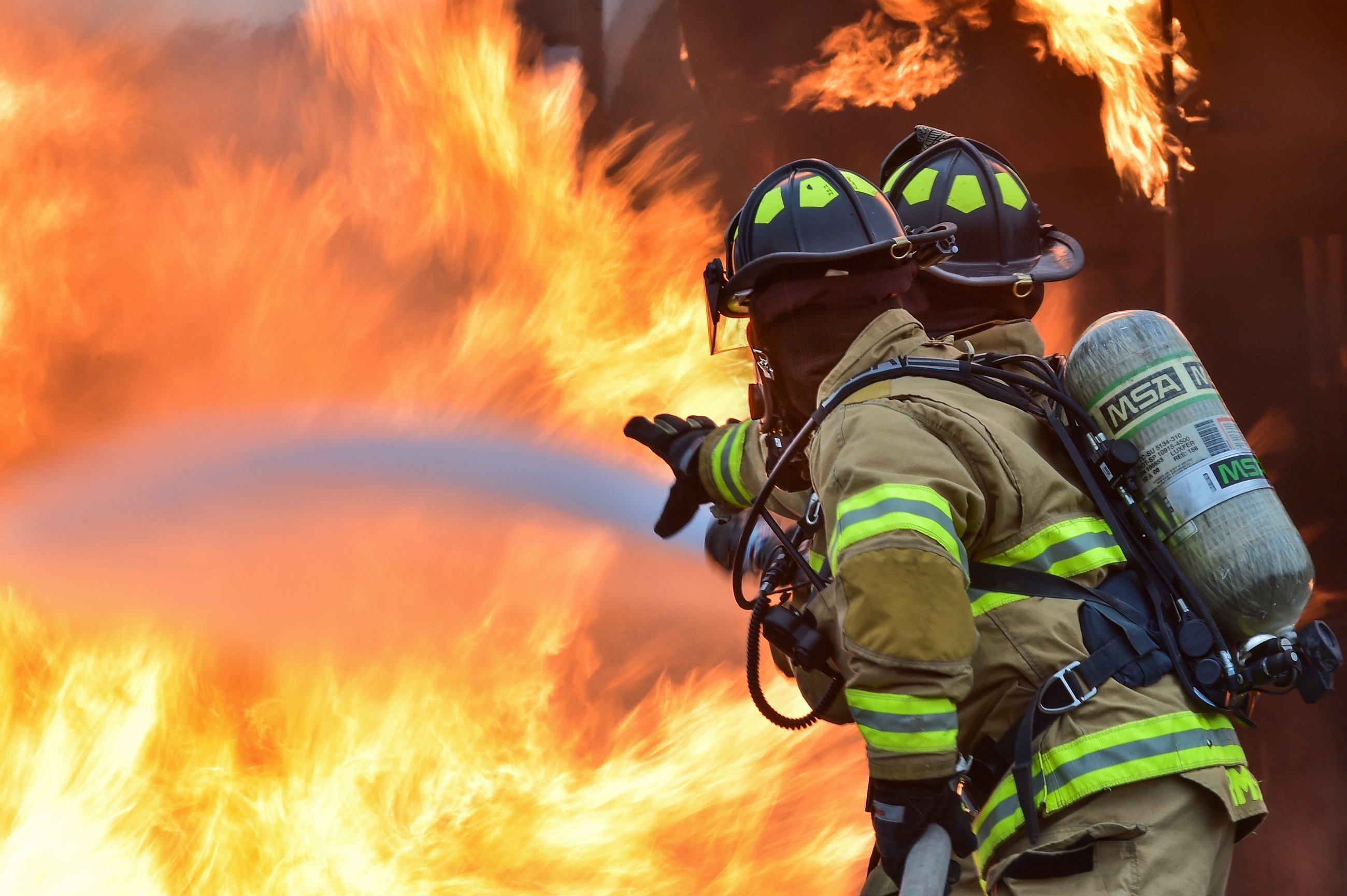 Firefighters battling a large fire with water HD Wallpaper
