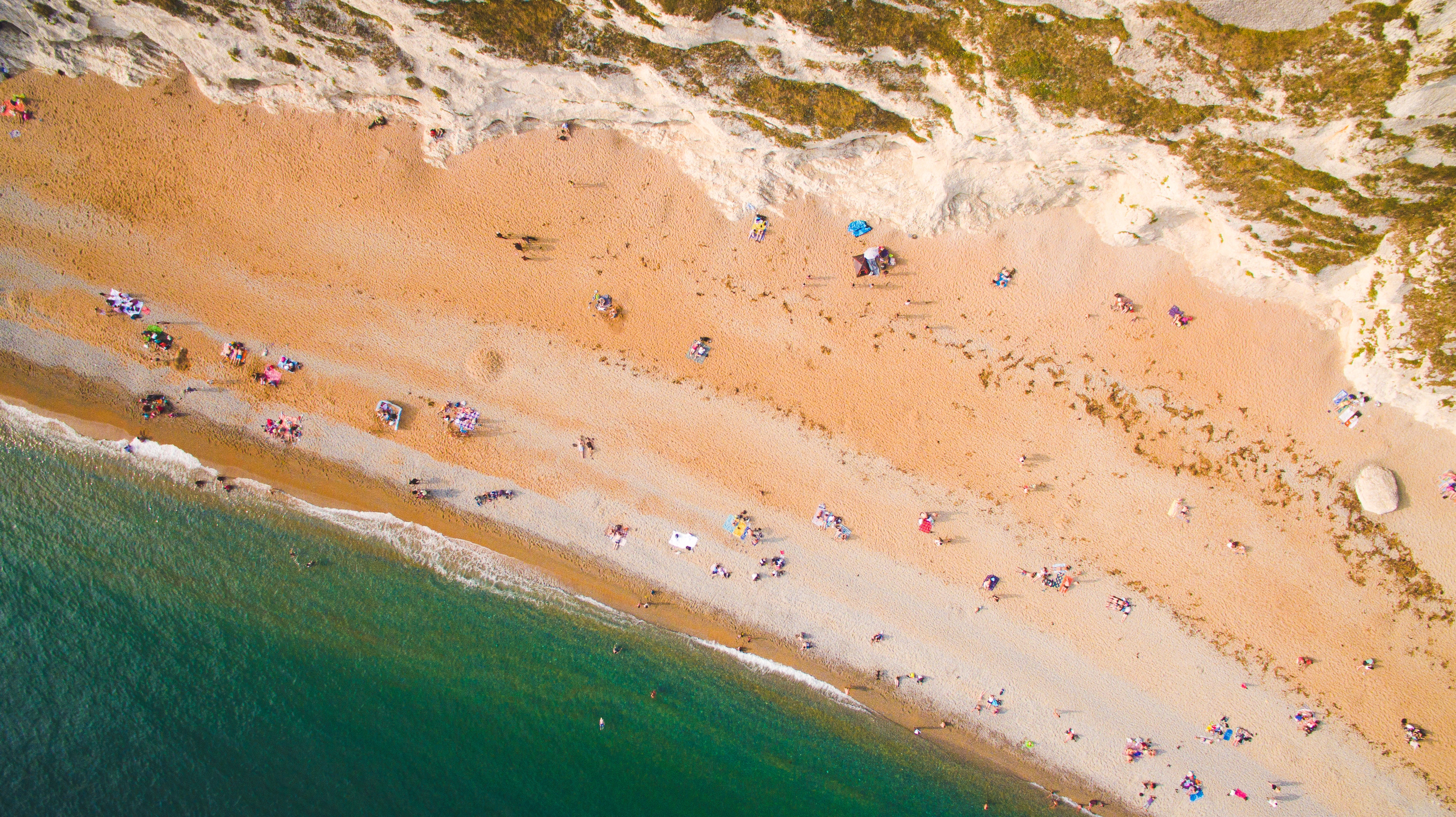 Aerial view of a crowded beach with white cliffs and turquoise water HD Wallpaper