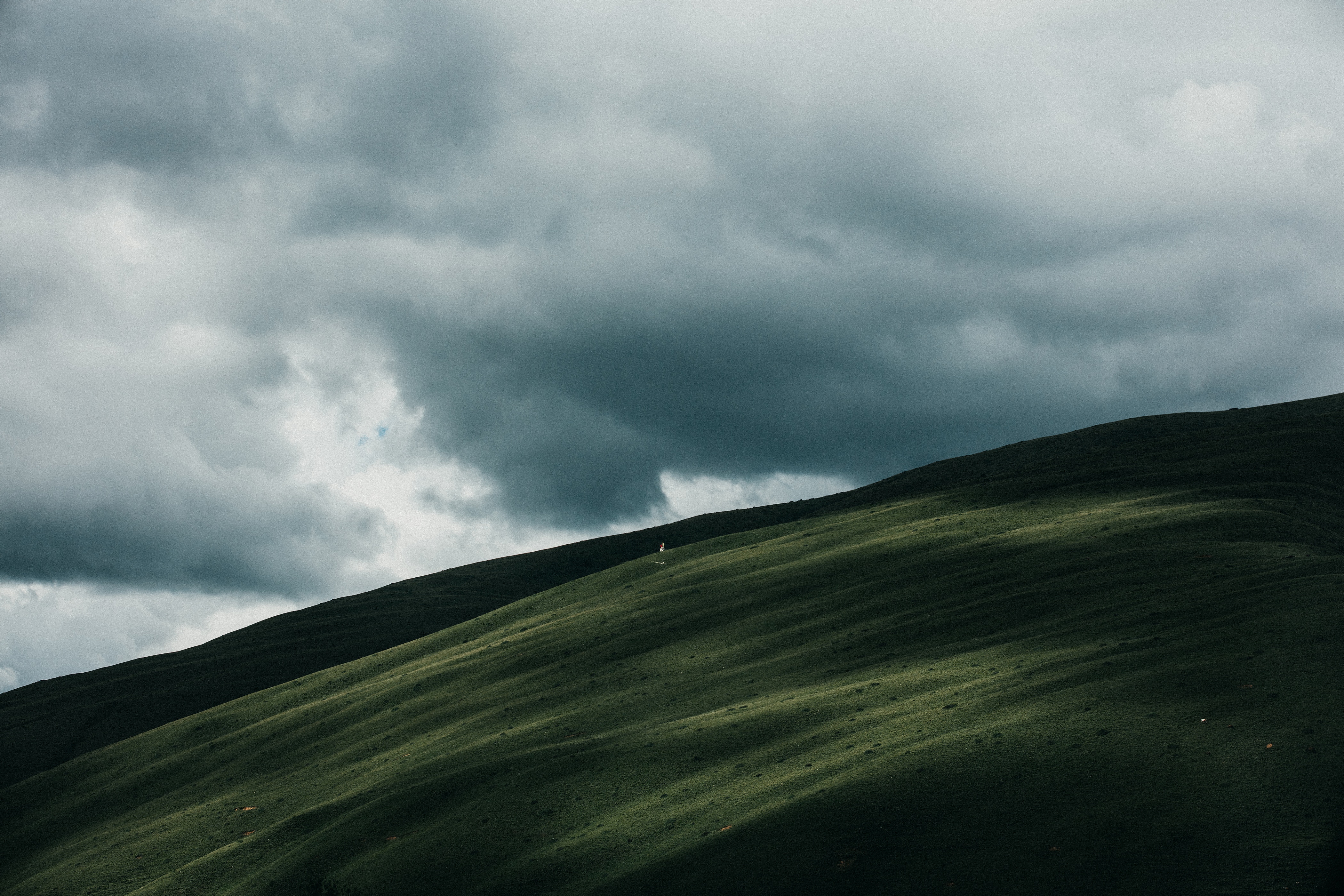 Green hills under cloudy sky HD Wallpaper