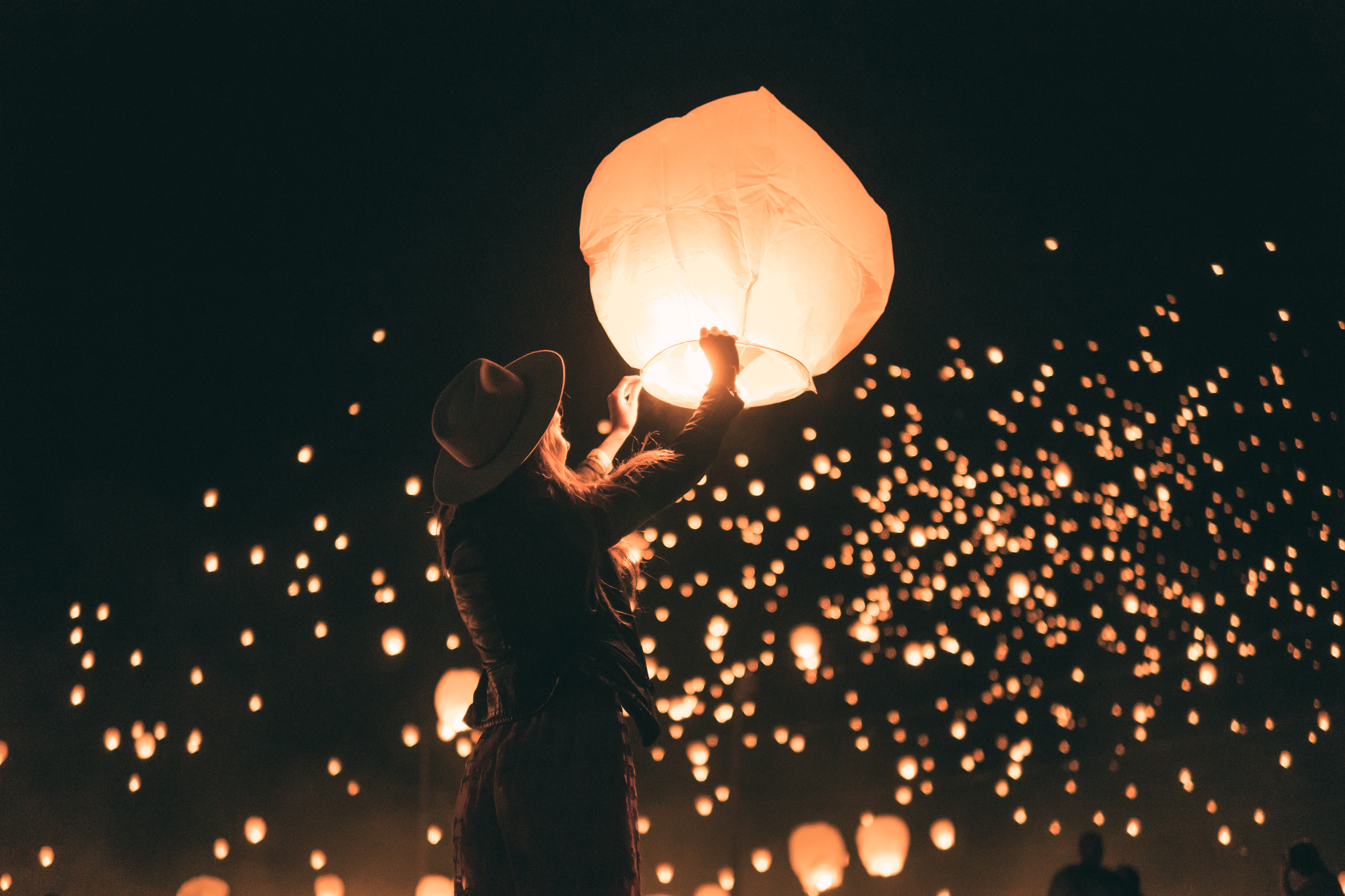 Woman releasing a sky lantern at a festival at night HD Wallpaper
