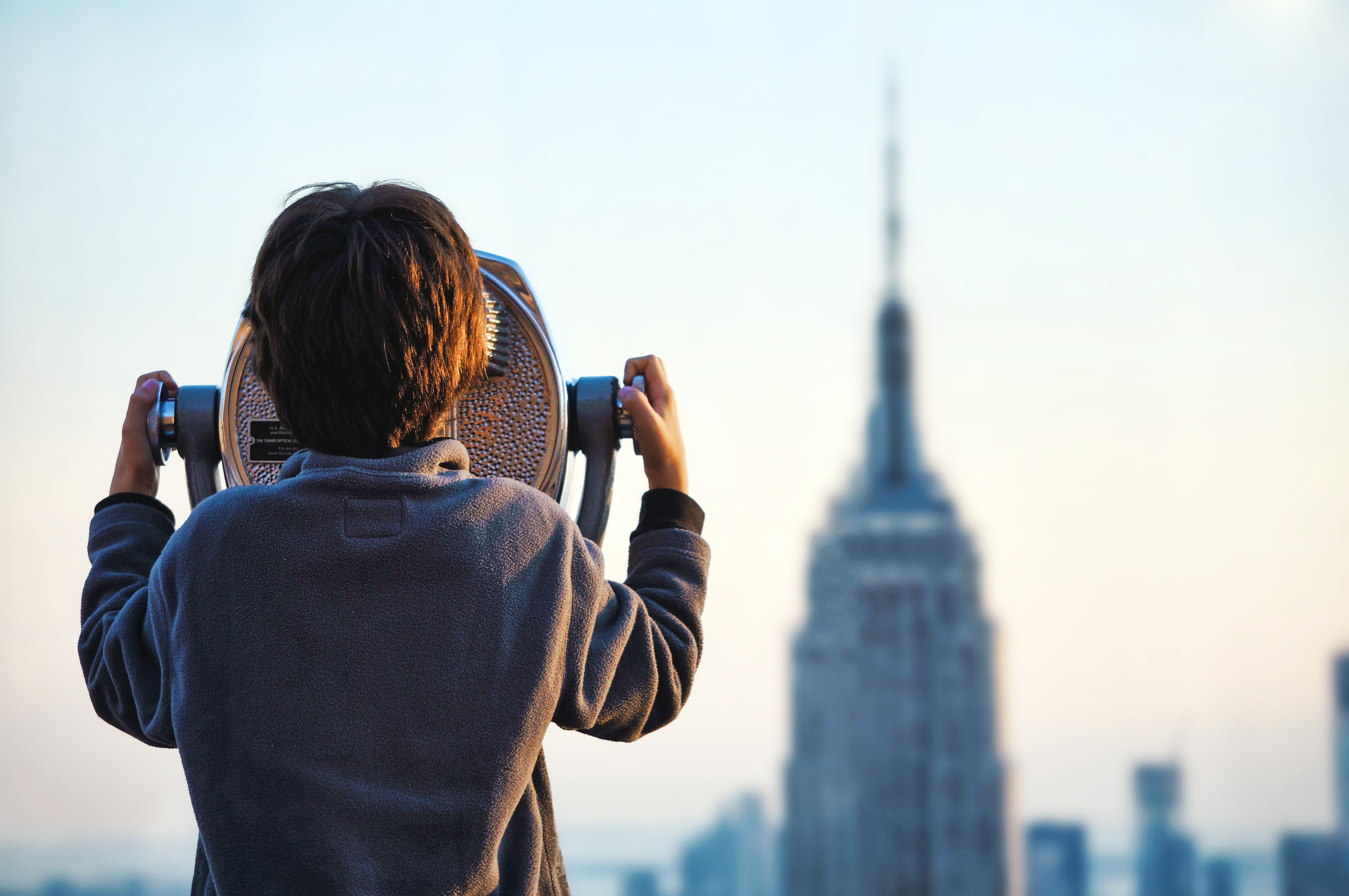 Boy looking through binoculars at Empire State Building HD Wallpaper