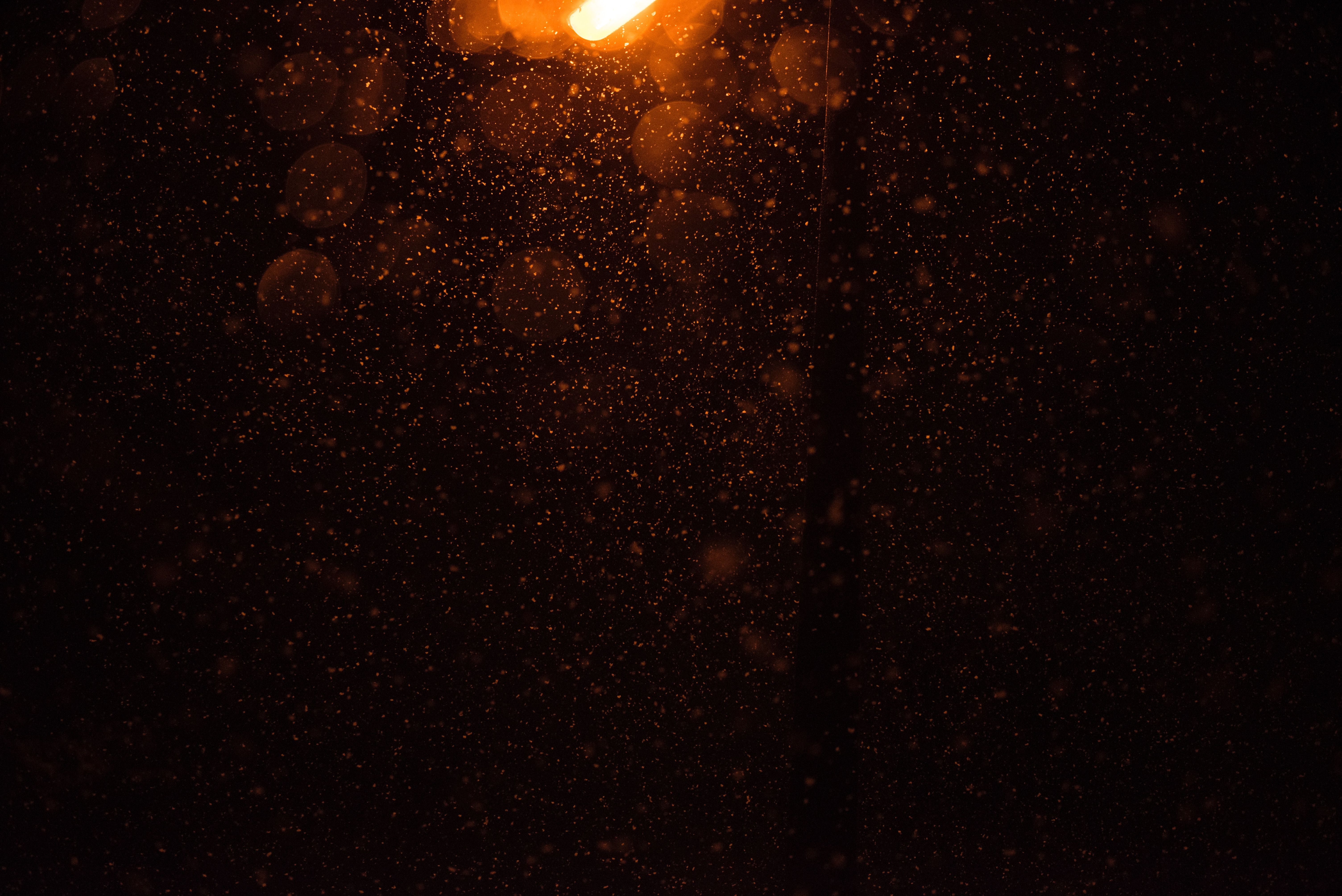 Snowing under a warm street lamp at night HD Wallpaper
