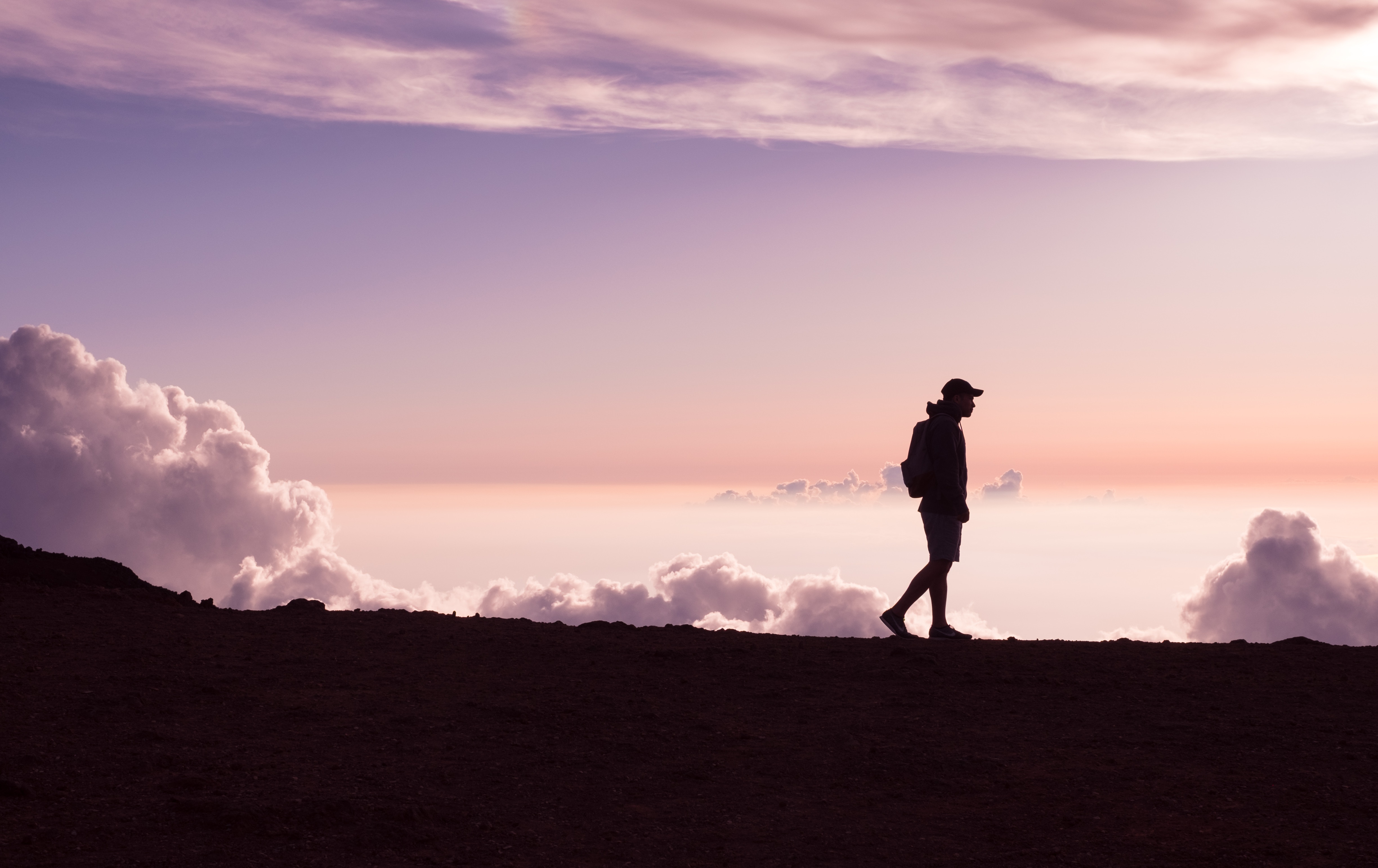 Silhouette of a man walking on a mountain at sunset HD Wallpaper