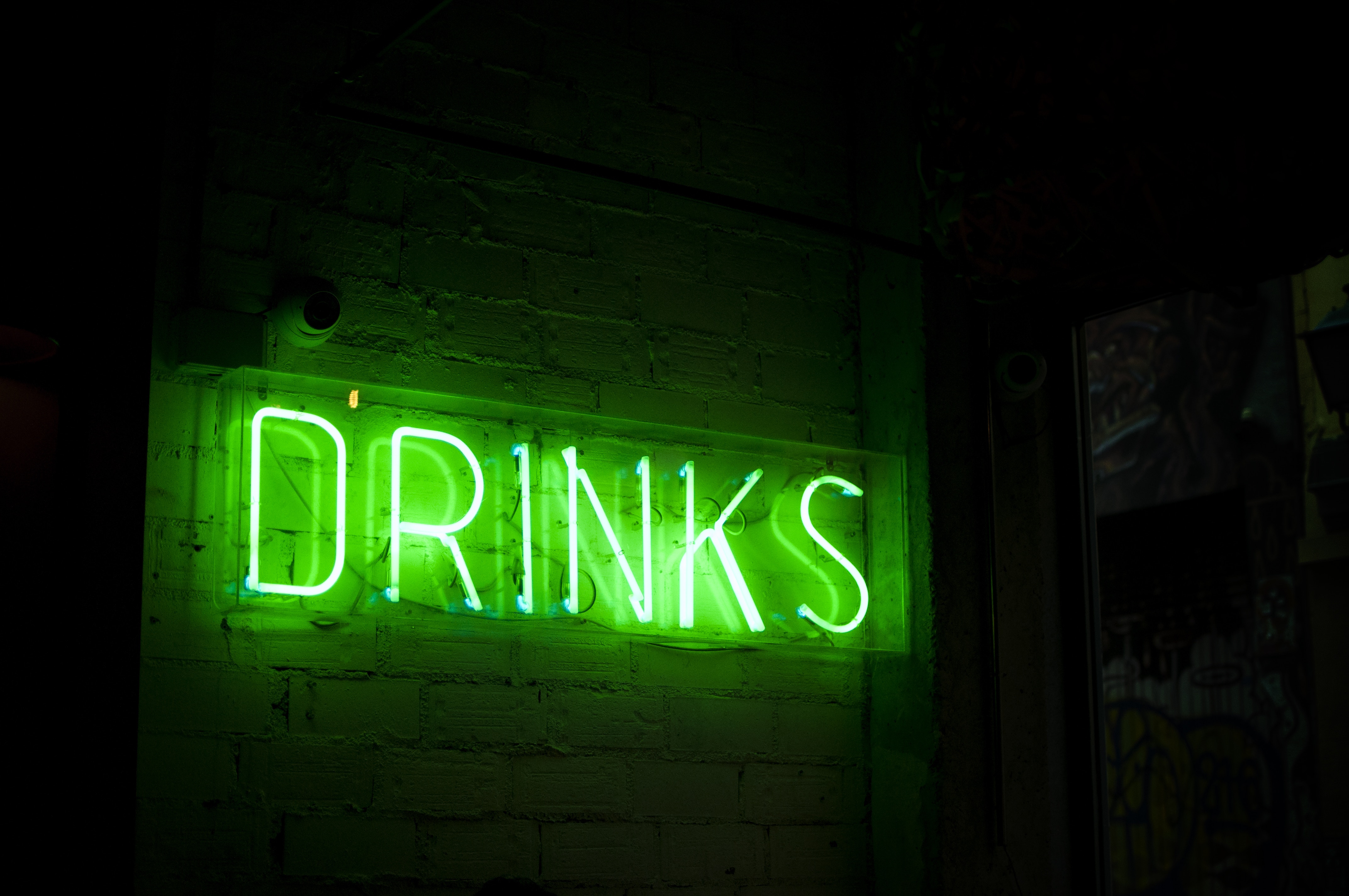 Green neon "DRINKS" sign on brick wall HD Wallpaper