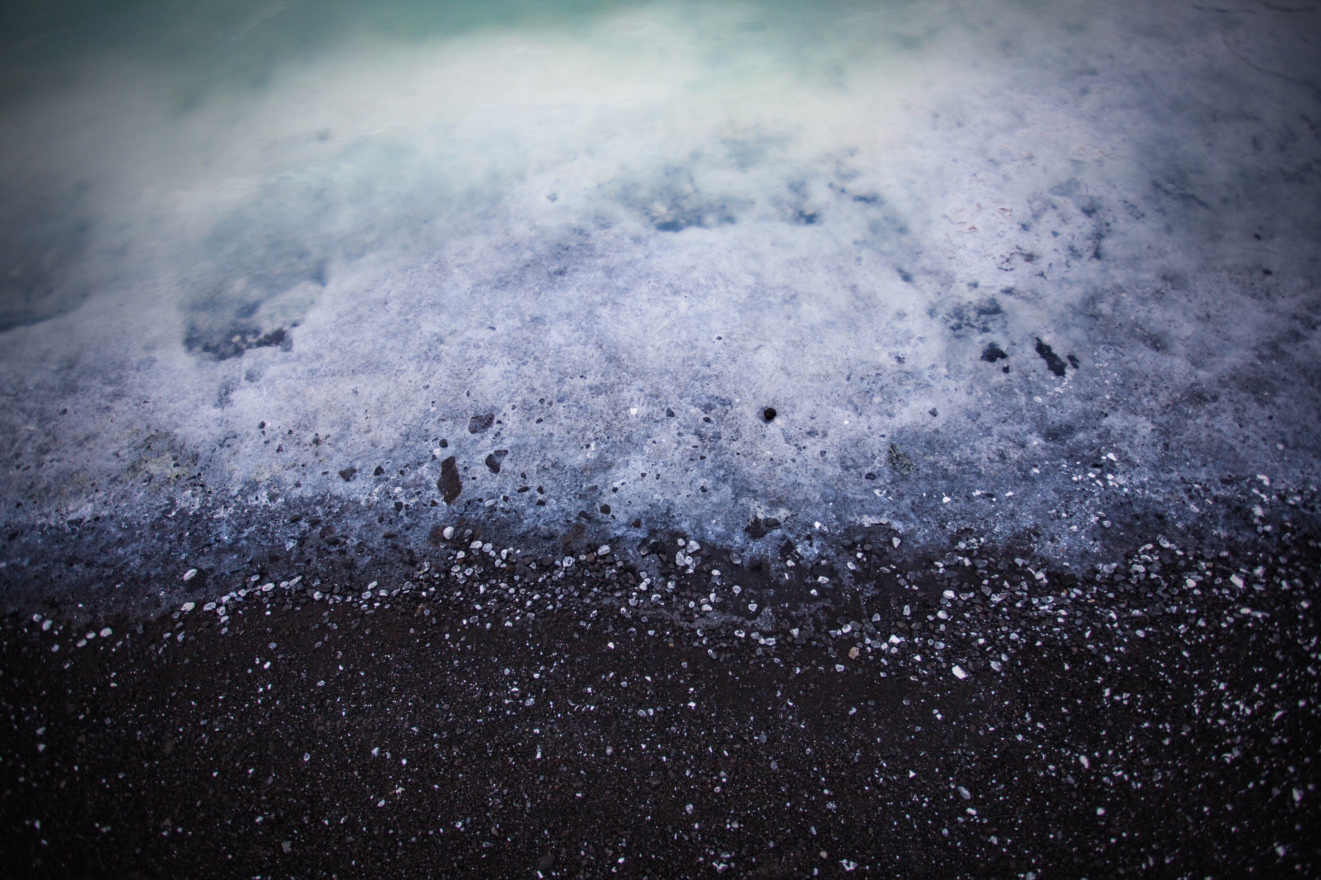 Black sand beach with foamy ocean waves HD Wallpaper