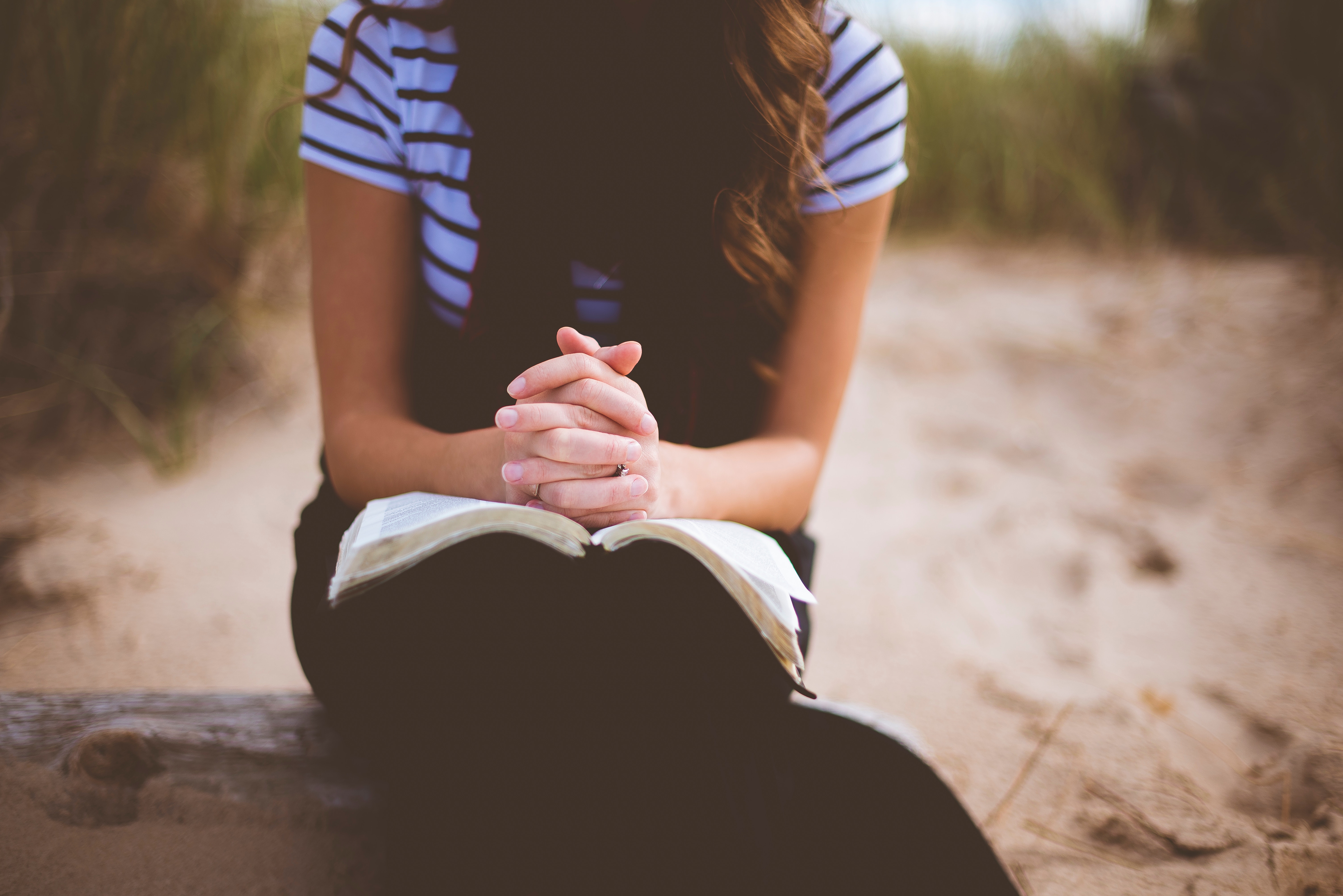 Woman praying with an open book on the sand HD Wallpaper