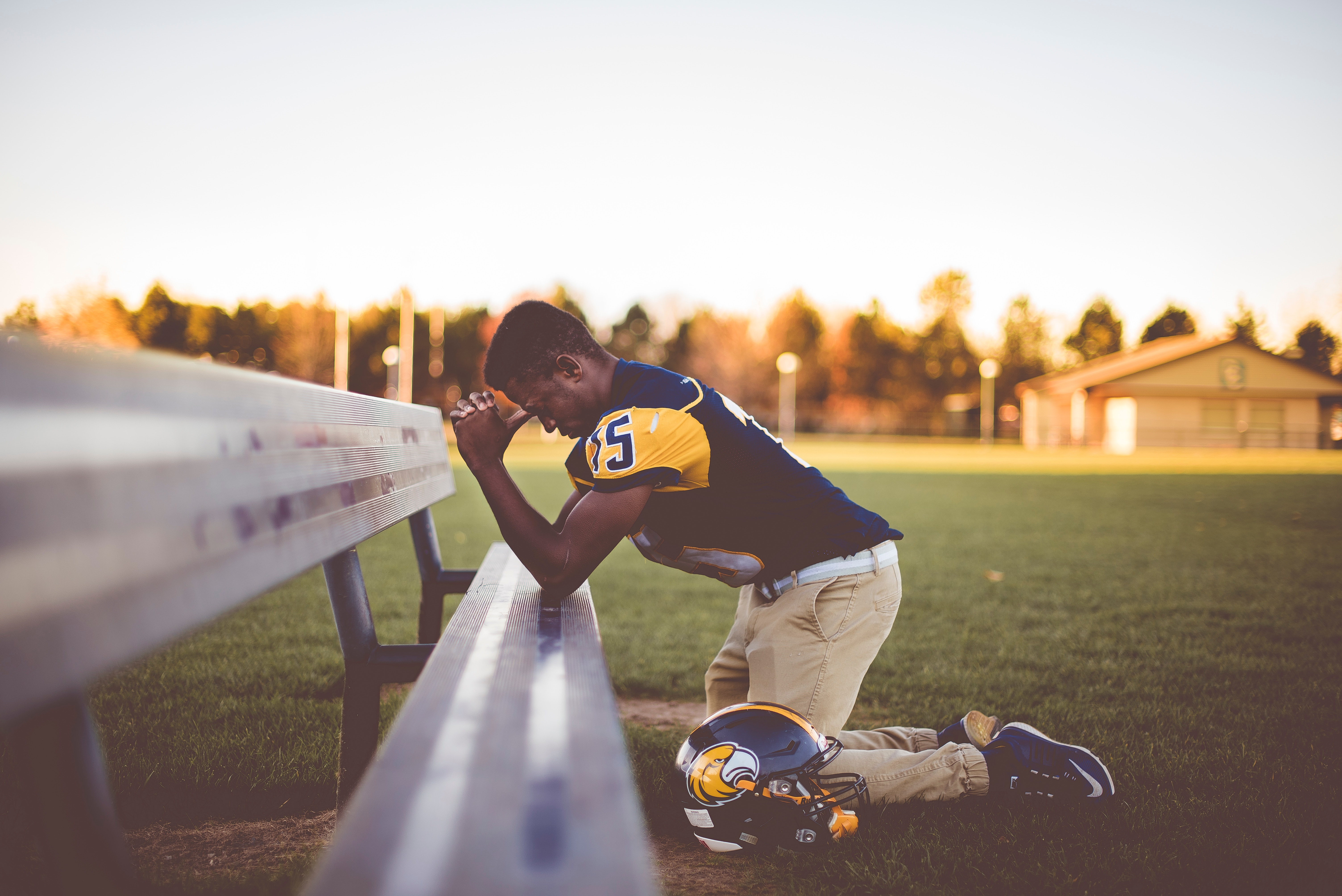 Football player praying on the field HD Wallpaper
