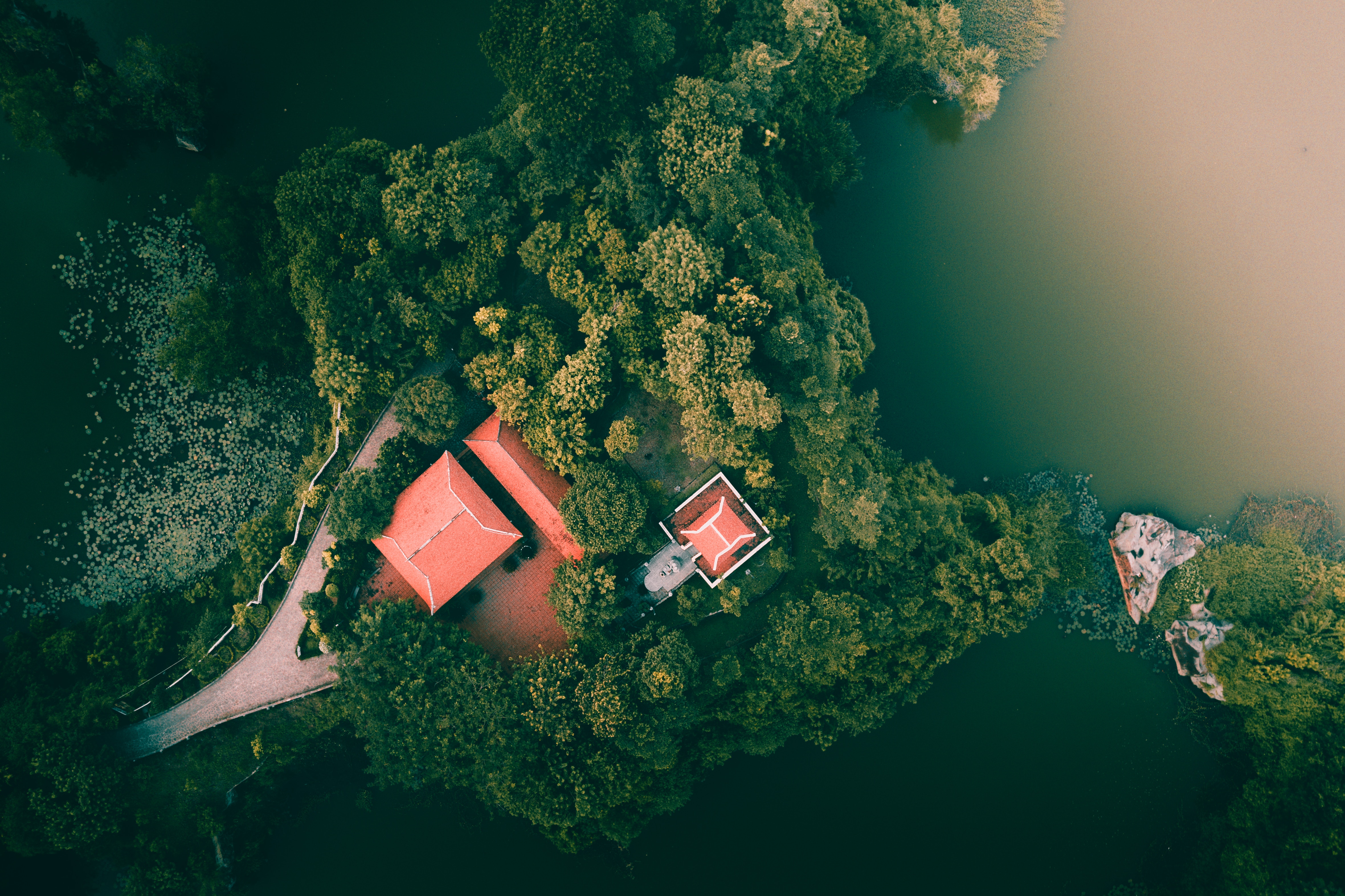 Aerial view of buildings and trees by a lake in Vietnam HD Wallpaper