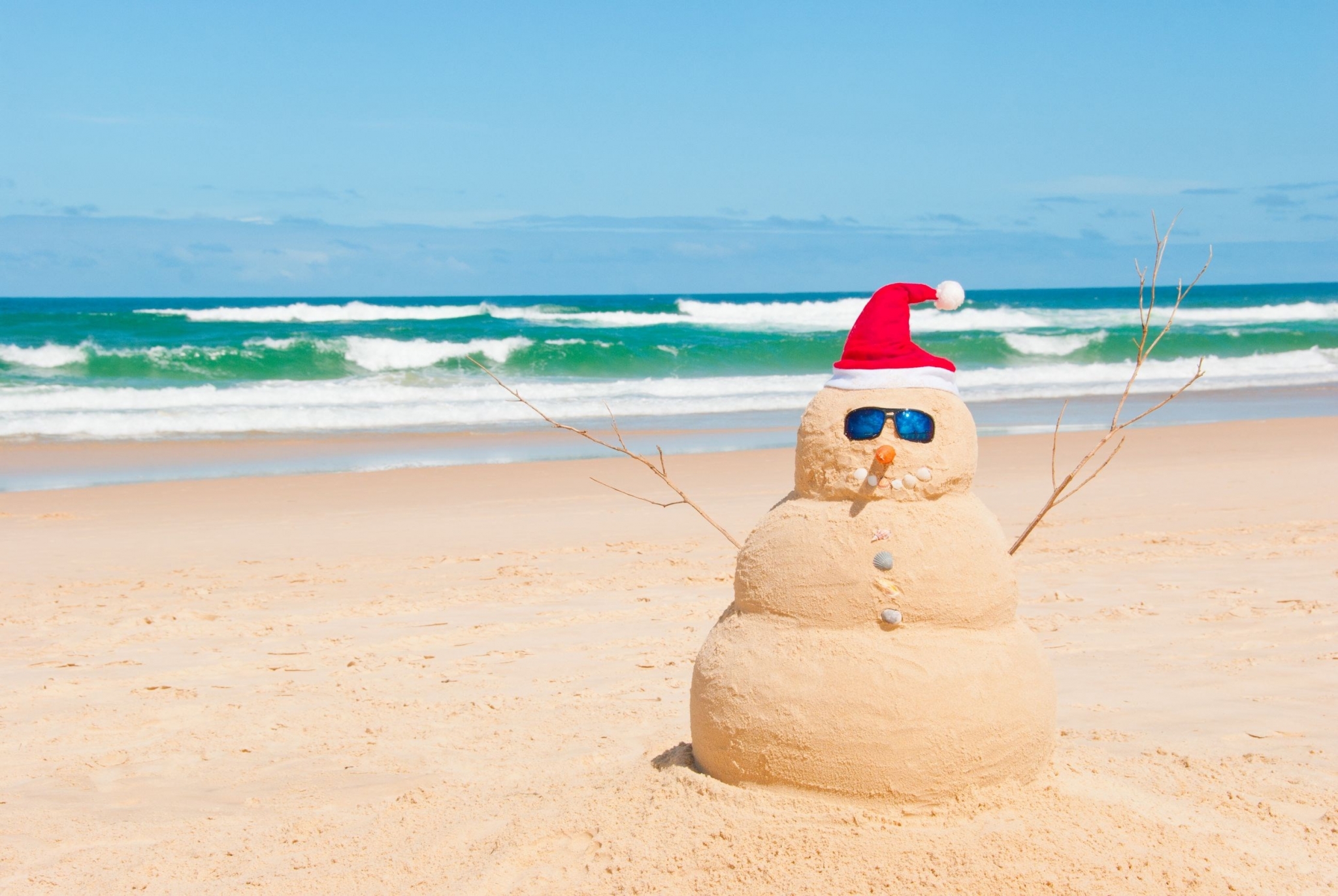 Sand snowman with Santa hat on beach HD Wallpaper