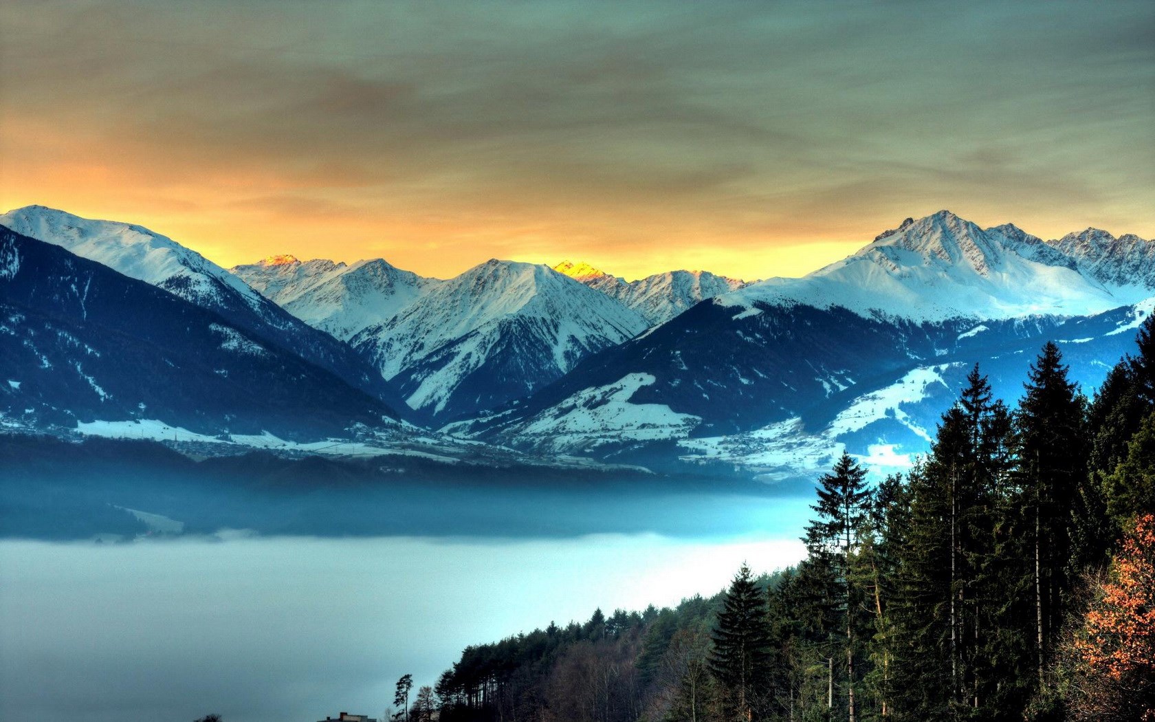 Snow-capped mountains at sunrise with fog and forest HD Wallpaper