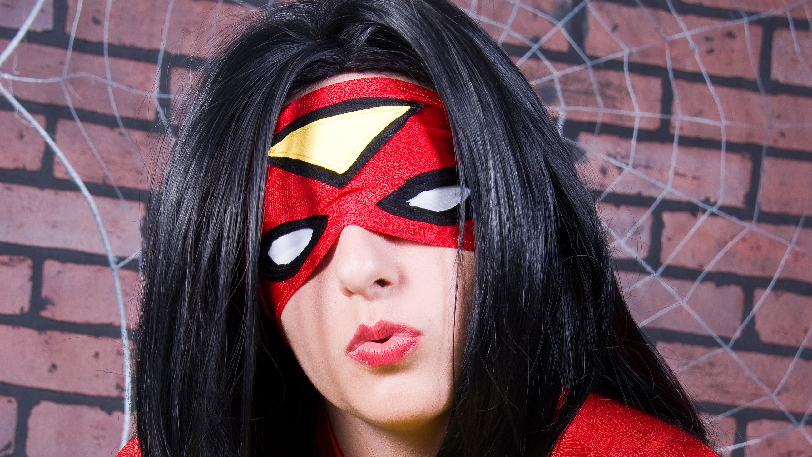 Spider-Woman cosplay in front of brick wall with spiderweb HD Wallpaper