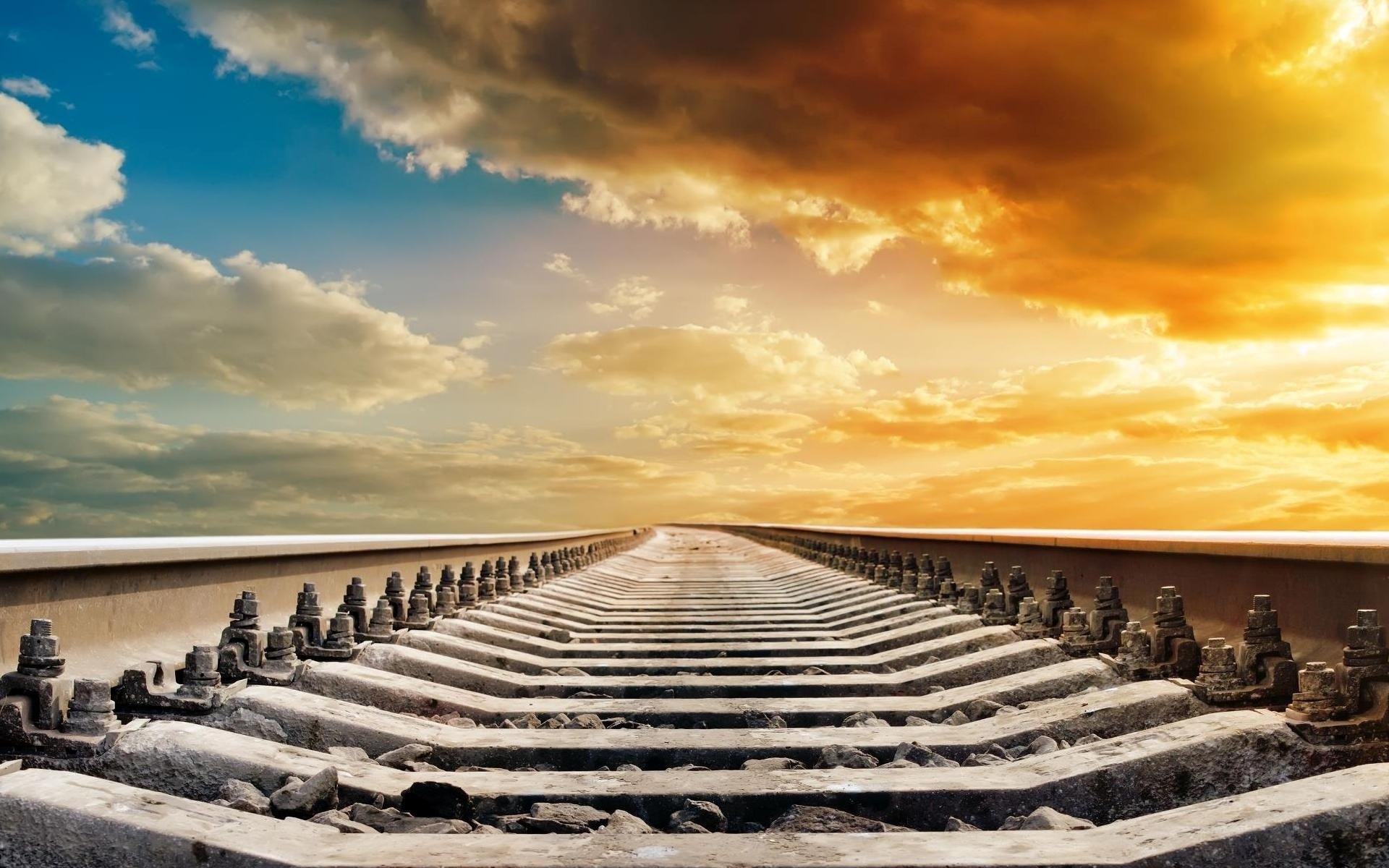 Railroad tracks leading to a dramatic sunset sky HD Wallpaper