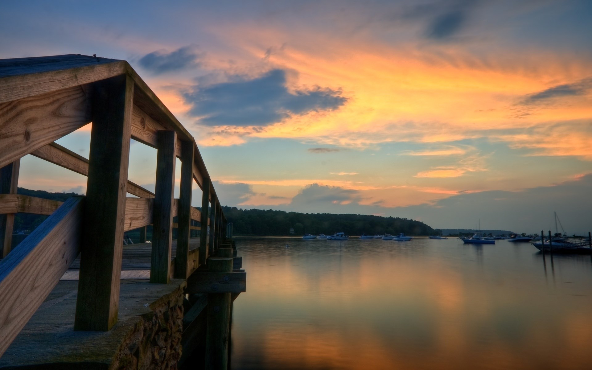 Wooden pier at sunset over a calm bay with boats HD Wallpaper