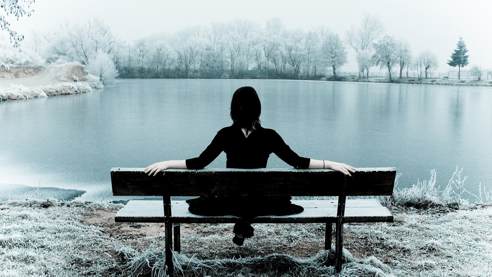 Woman sitting on a bench by a frozen lake HD Wallpaper