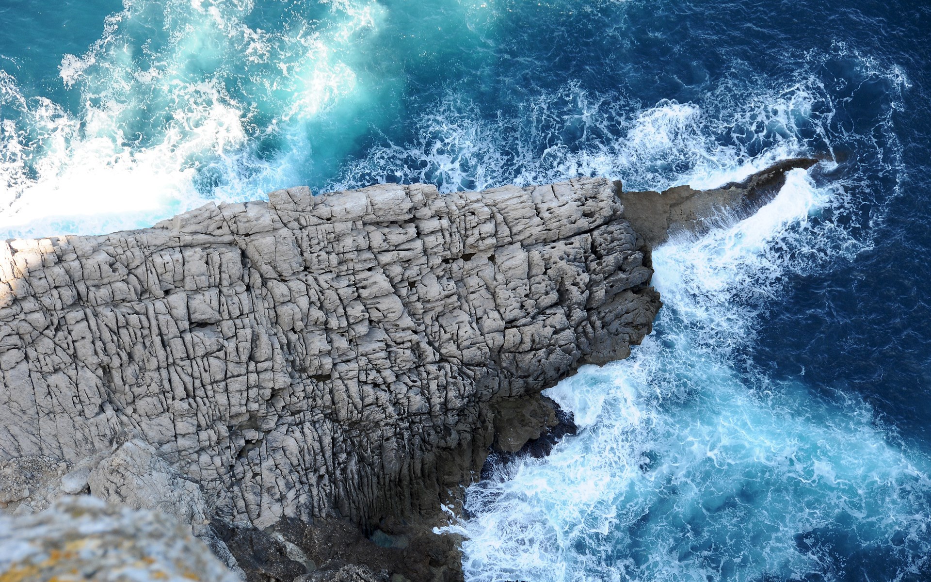 Waves crashing against a rocky cliff face HD Wallpaper