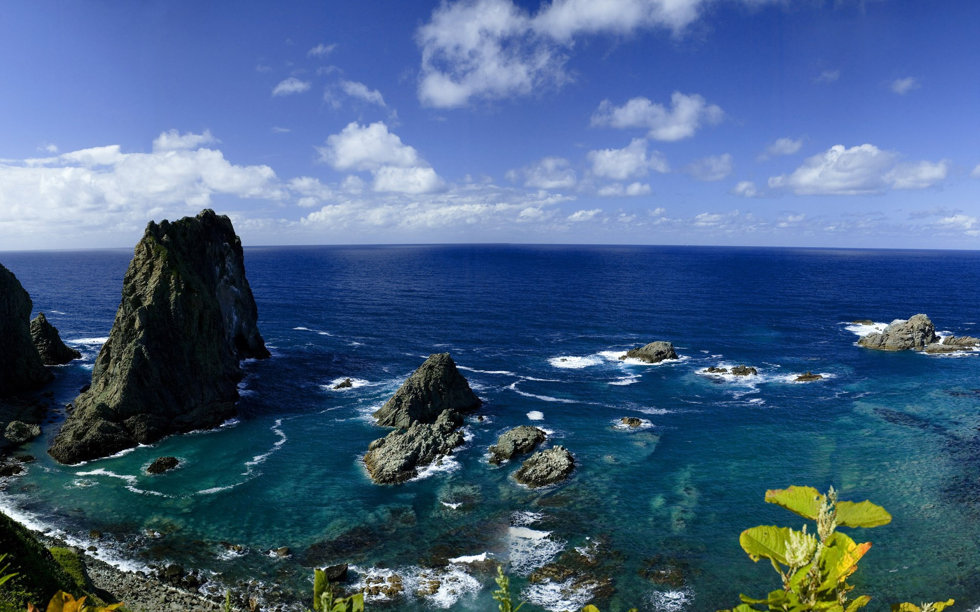 Rocky coastline with blue ocean and white clouds HD Wallpaper
