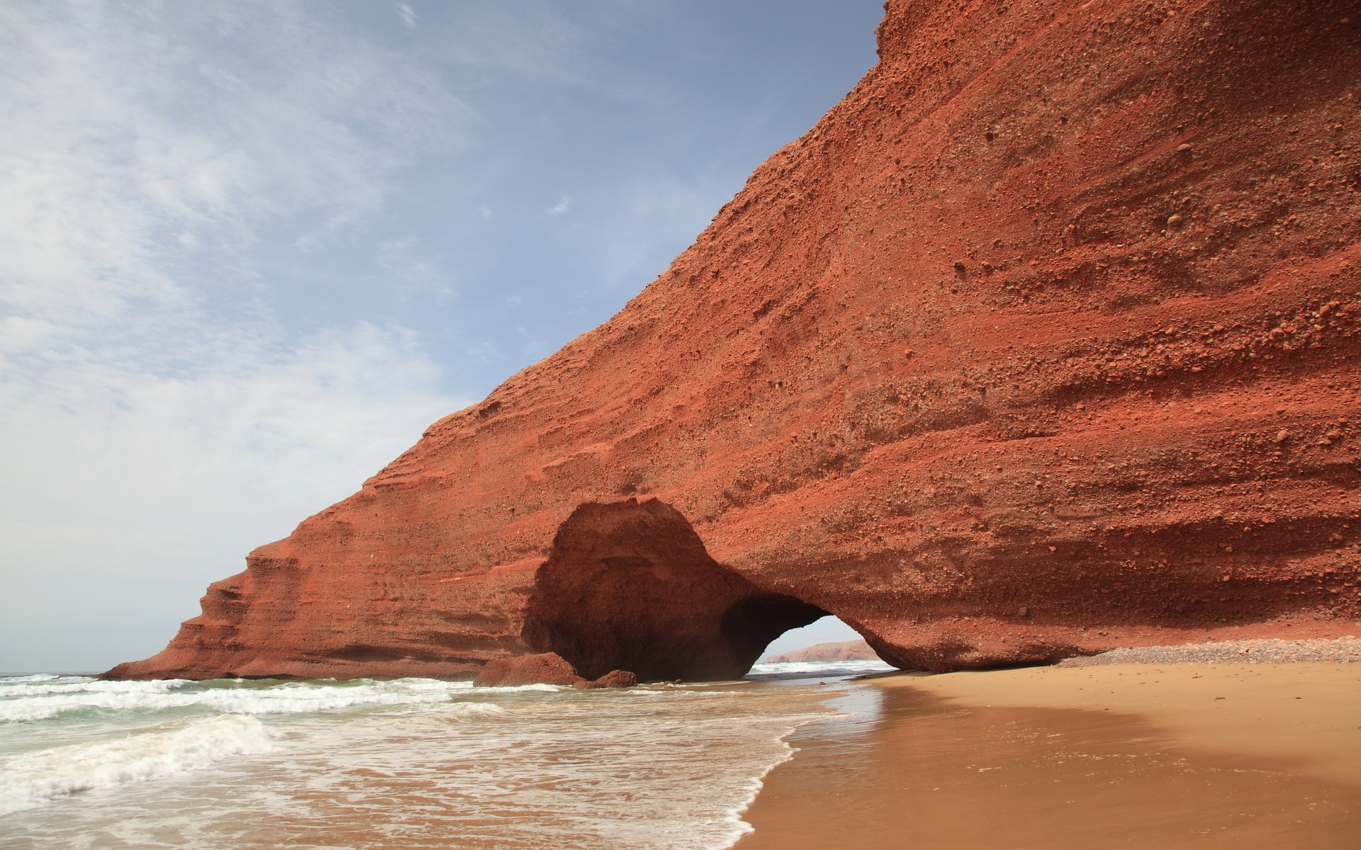 Red rock archway on a beach with waves HD Wallpaper