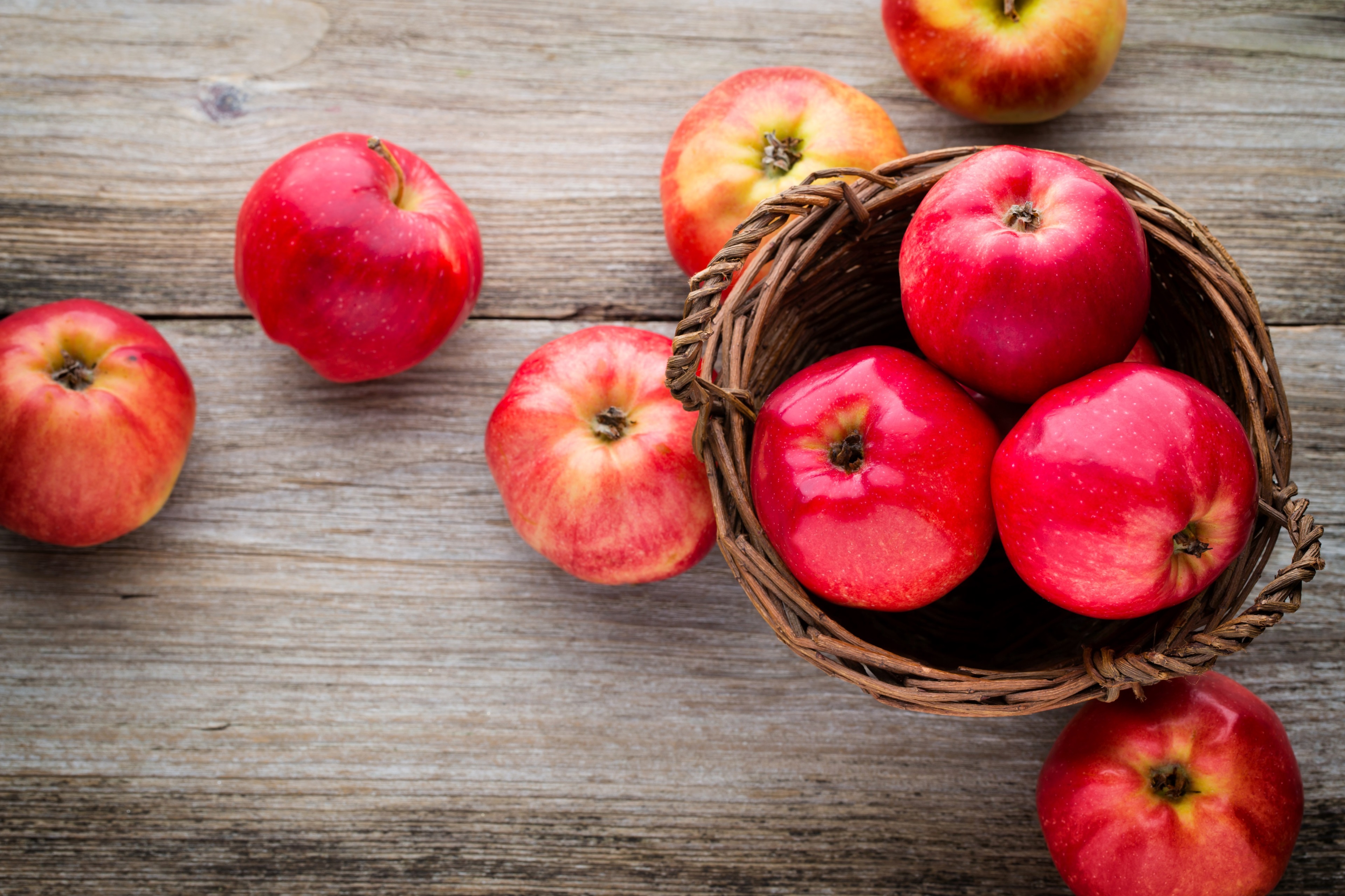 Red apples in a basket on wooden table 4K HD Wallpaper