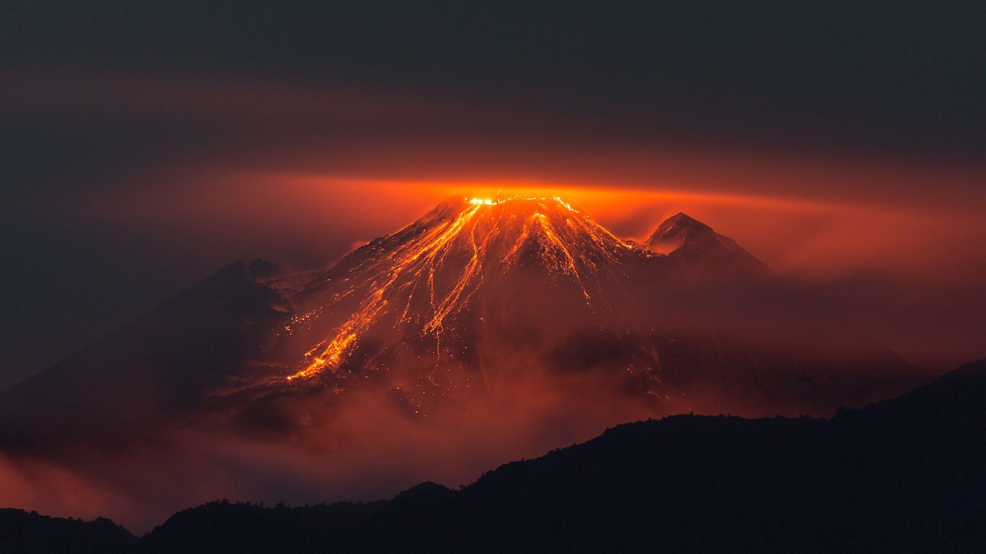 Volcano erupting with lava flow at night HD Wallpaper