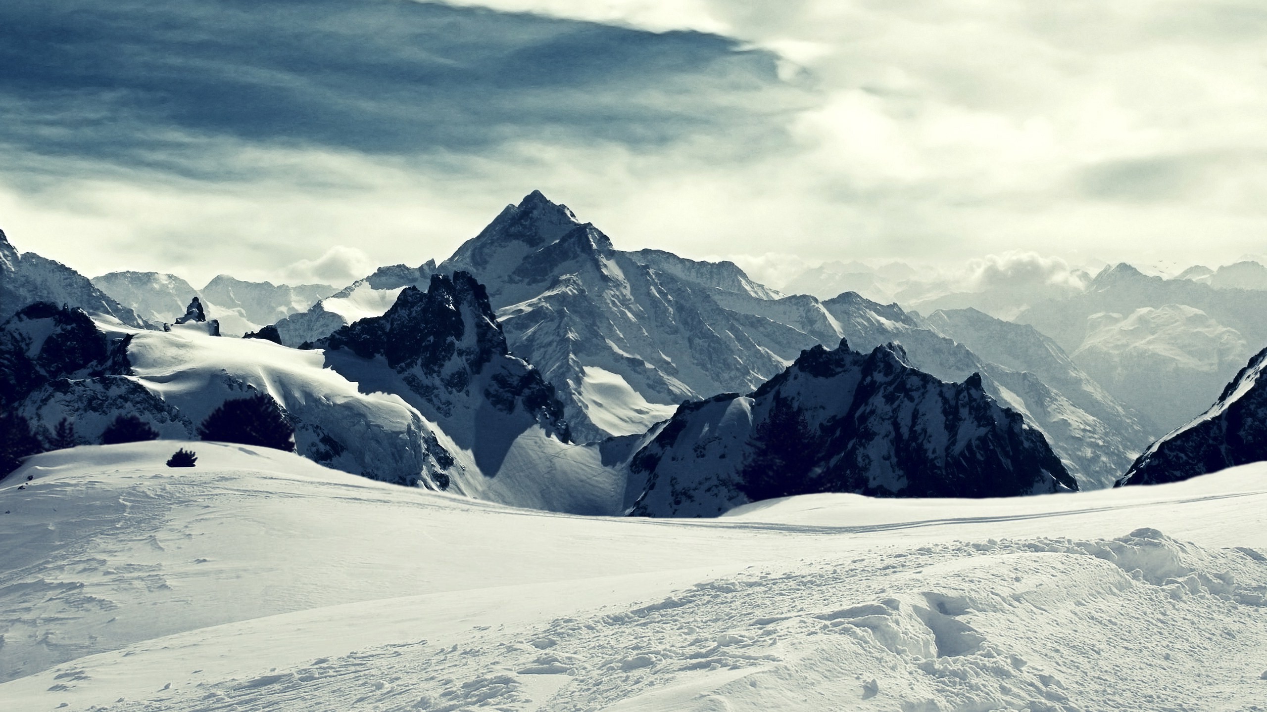Snowy mountain range under a cloudy sky HD Wallpaper