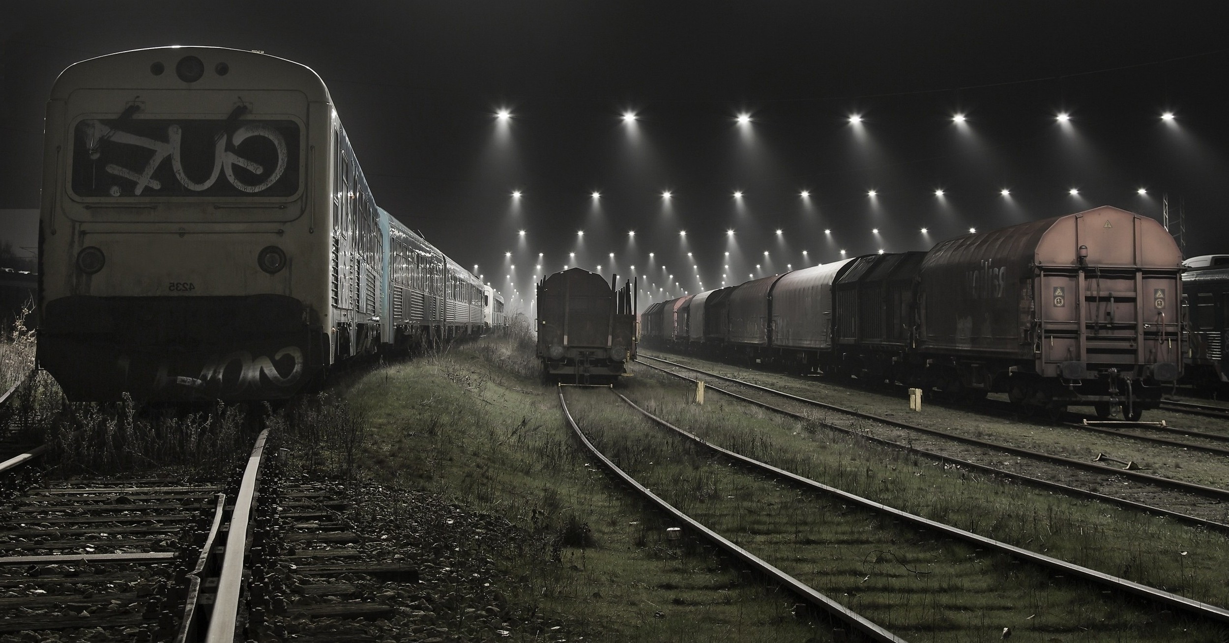 Trains at a foggy railyard at night with stadium lights HD Wallpaper