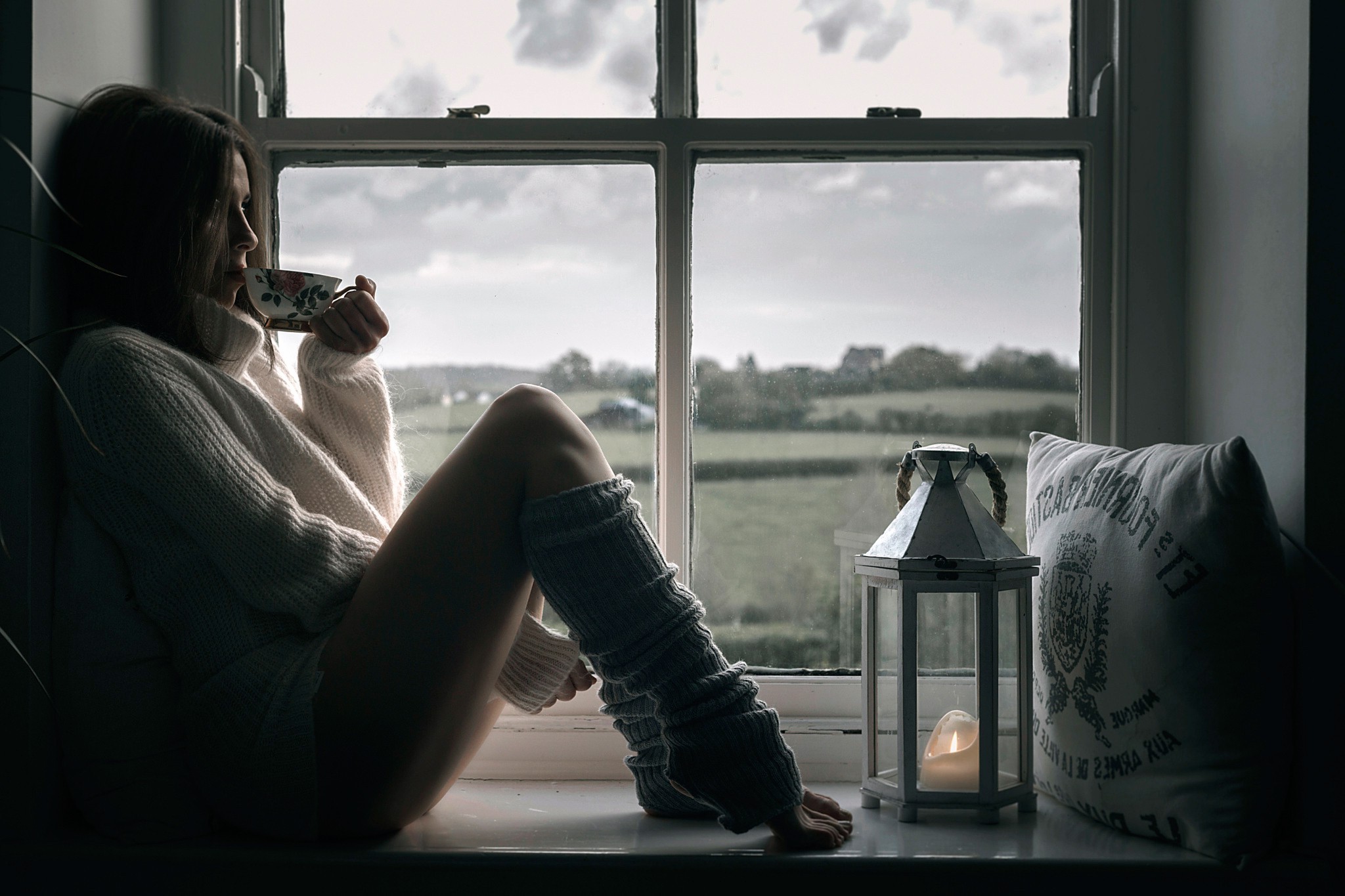 Woman in sweater drinking tea by window HD Wallpaper