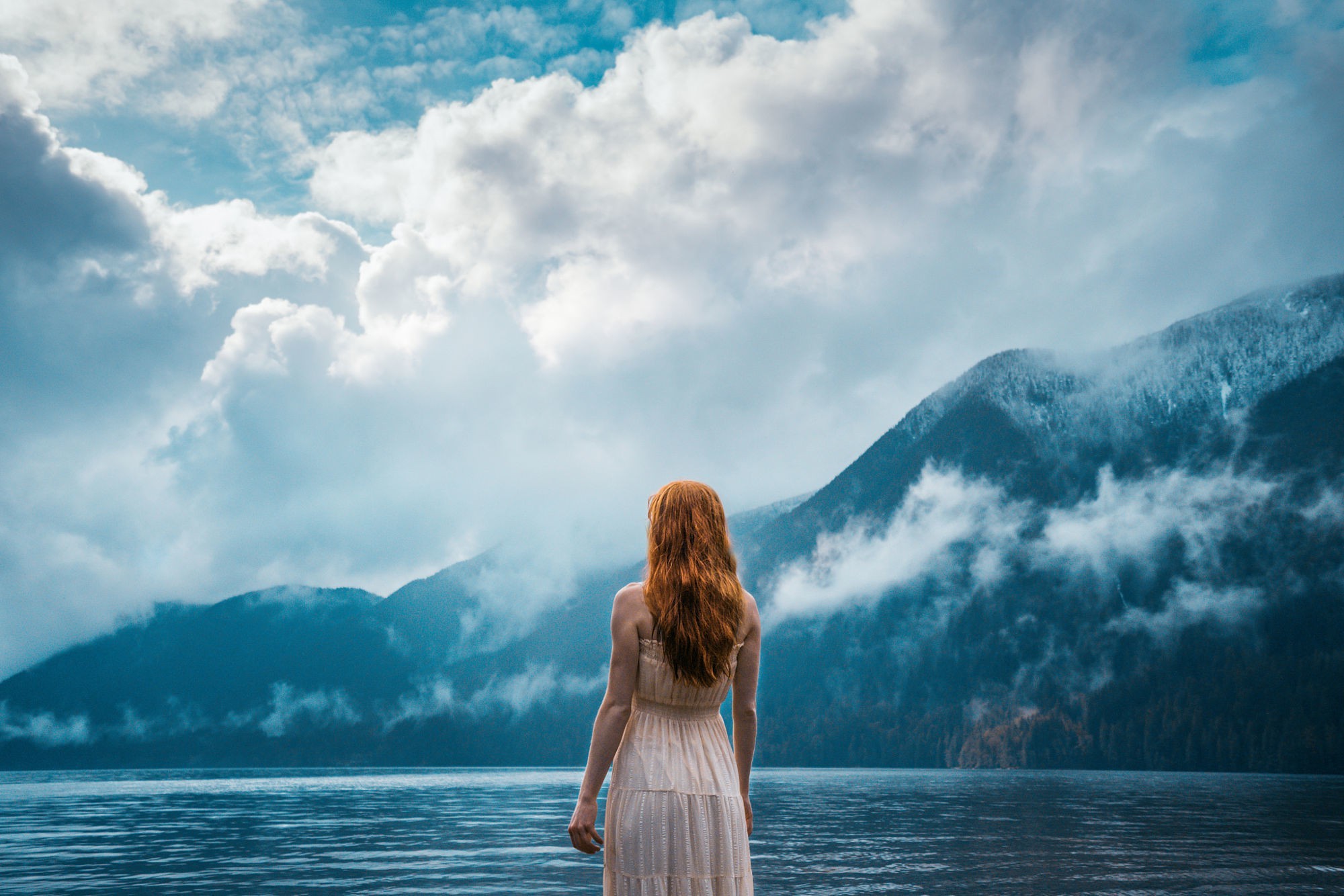 Woman in dress by a lake with mountains and clouds HD Wallpaper