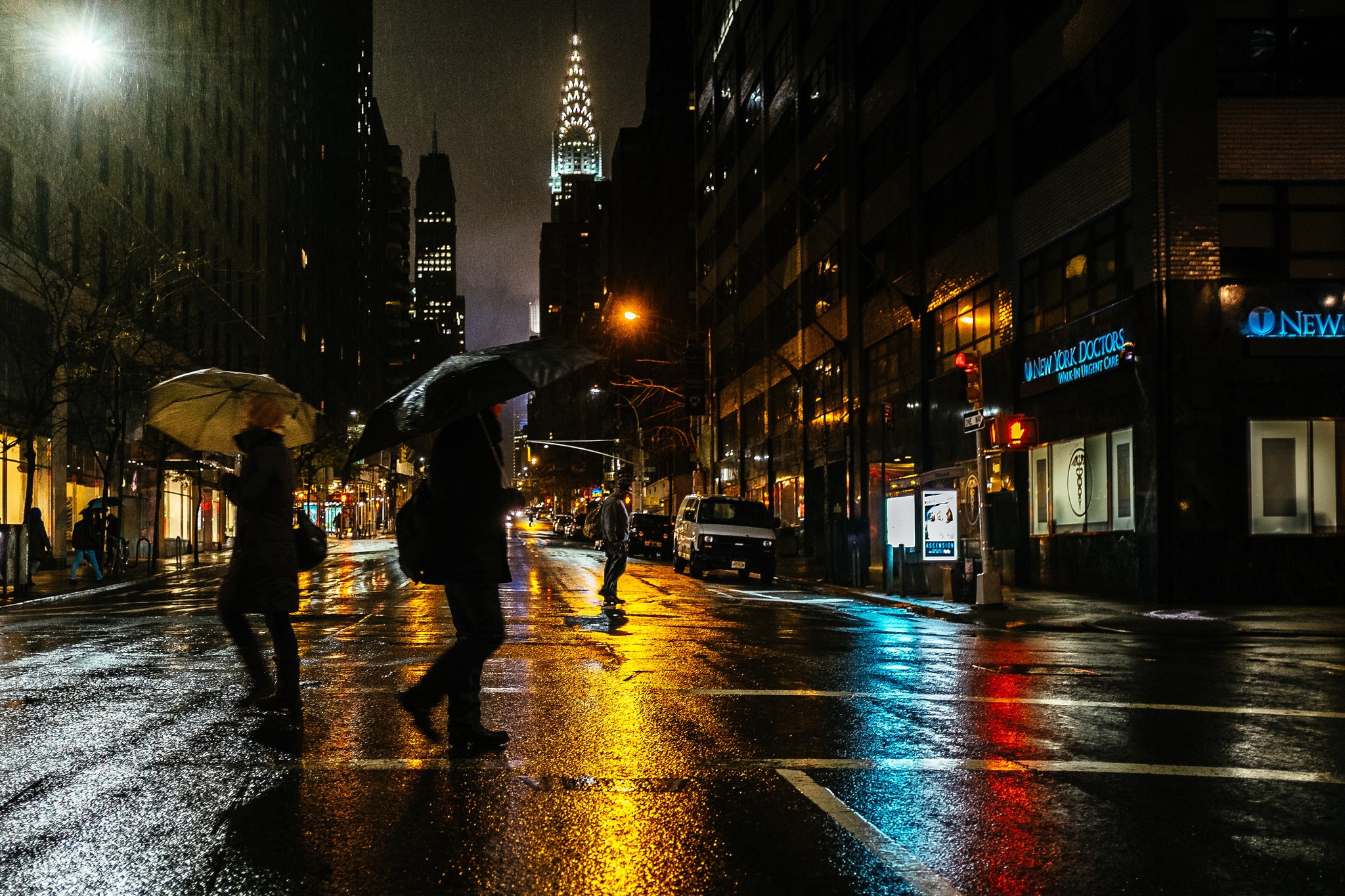 People with umbrellas crossing a wet street in New York City at night HD Wallpaper