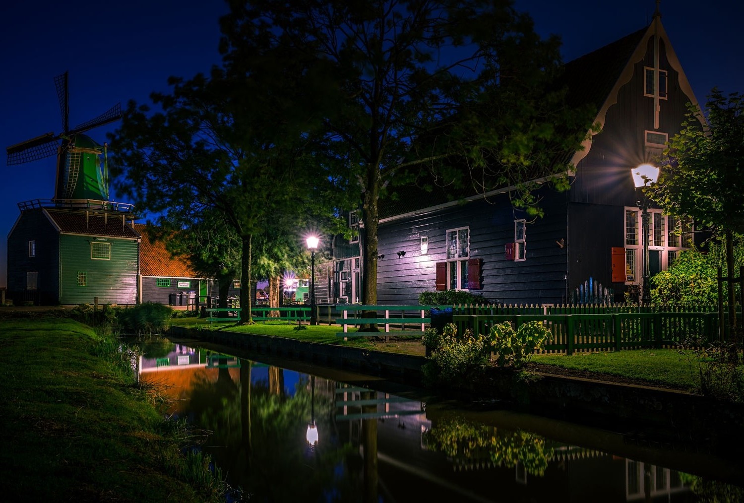 Windmill and houses by canal at night in Netherlands HD Wallpaper