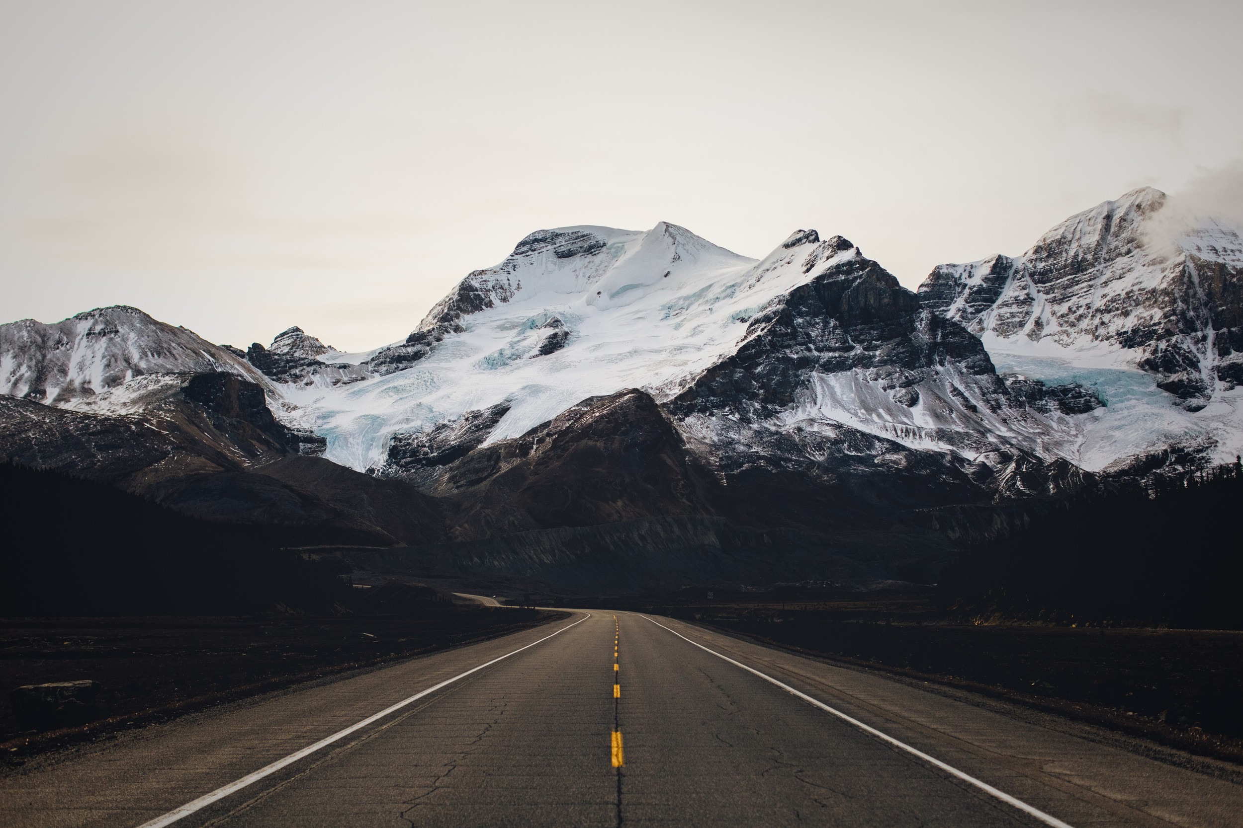 Road leading to snow-capped mountains HD Wallpaper