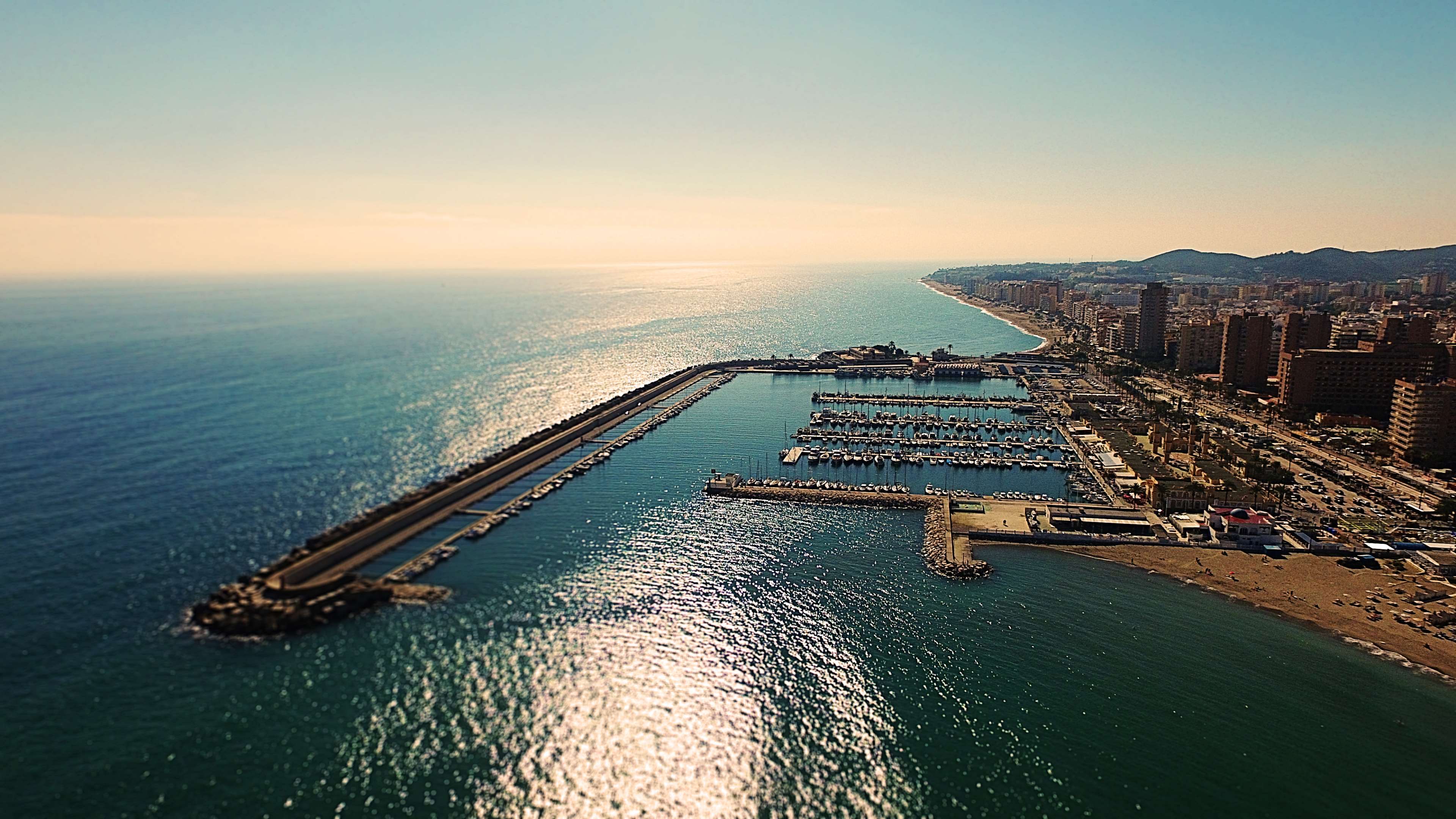 Aerial view of a coastal city with a harbor and ocean HD Wallpaper