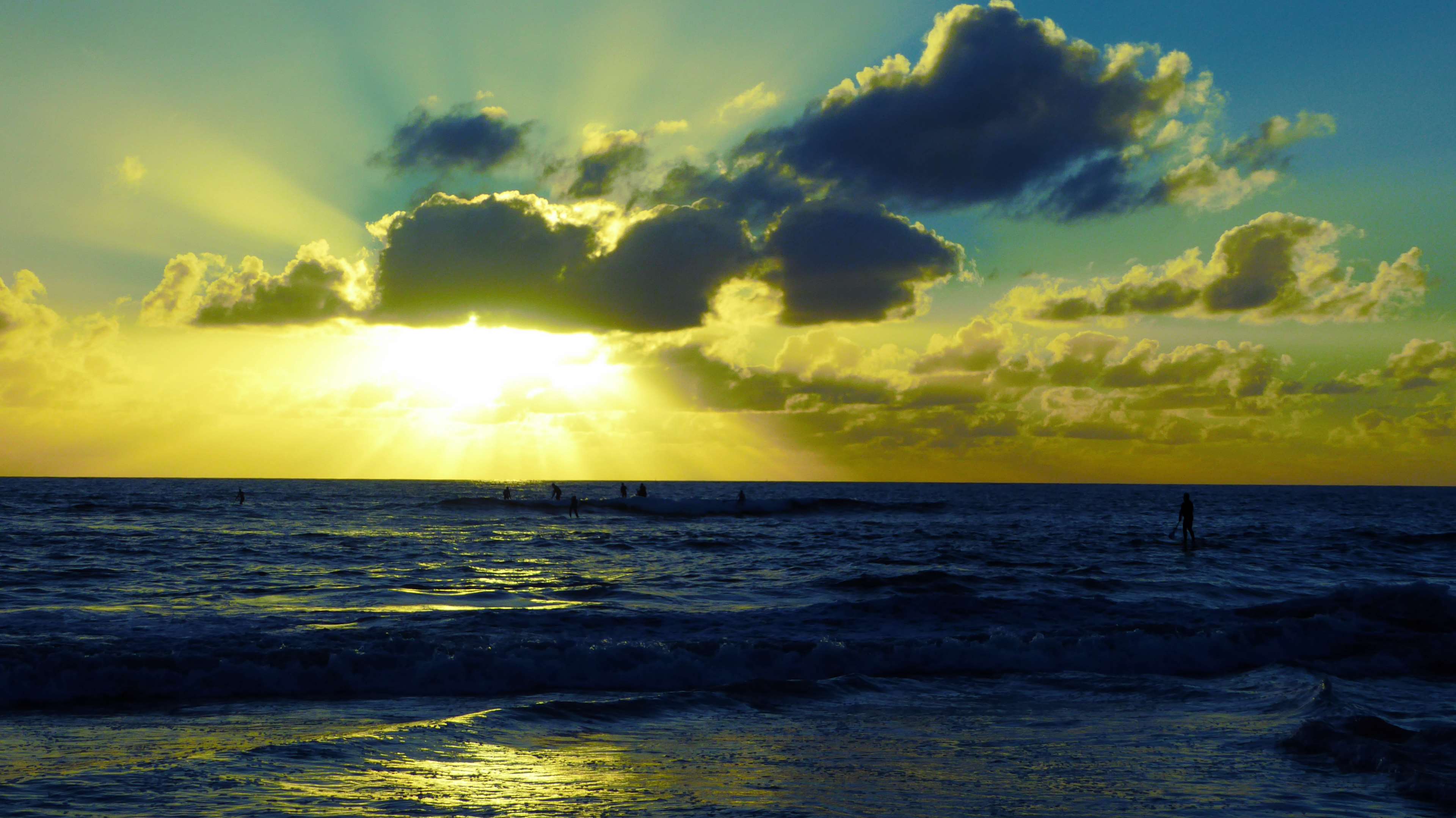Sunset over the sea with clouds and surfers HD Wallpaper