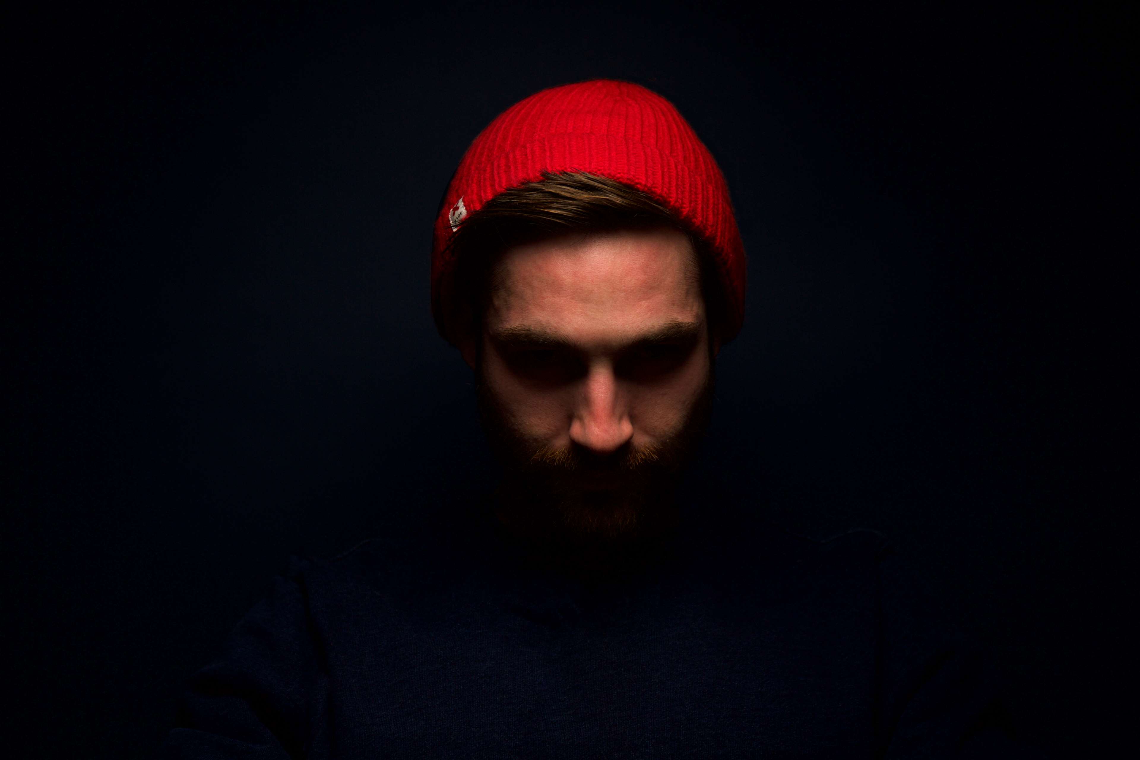 Man wearing a red beanie in dark studio portrait HD Wallpaper