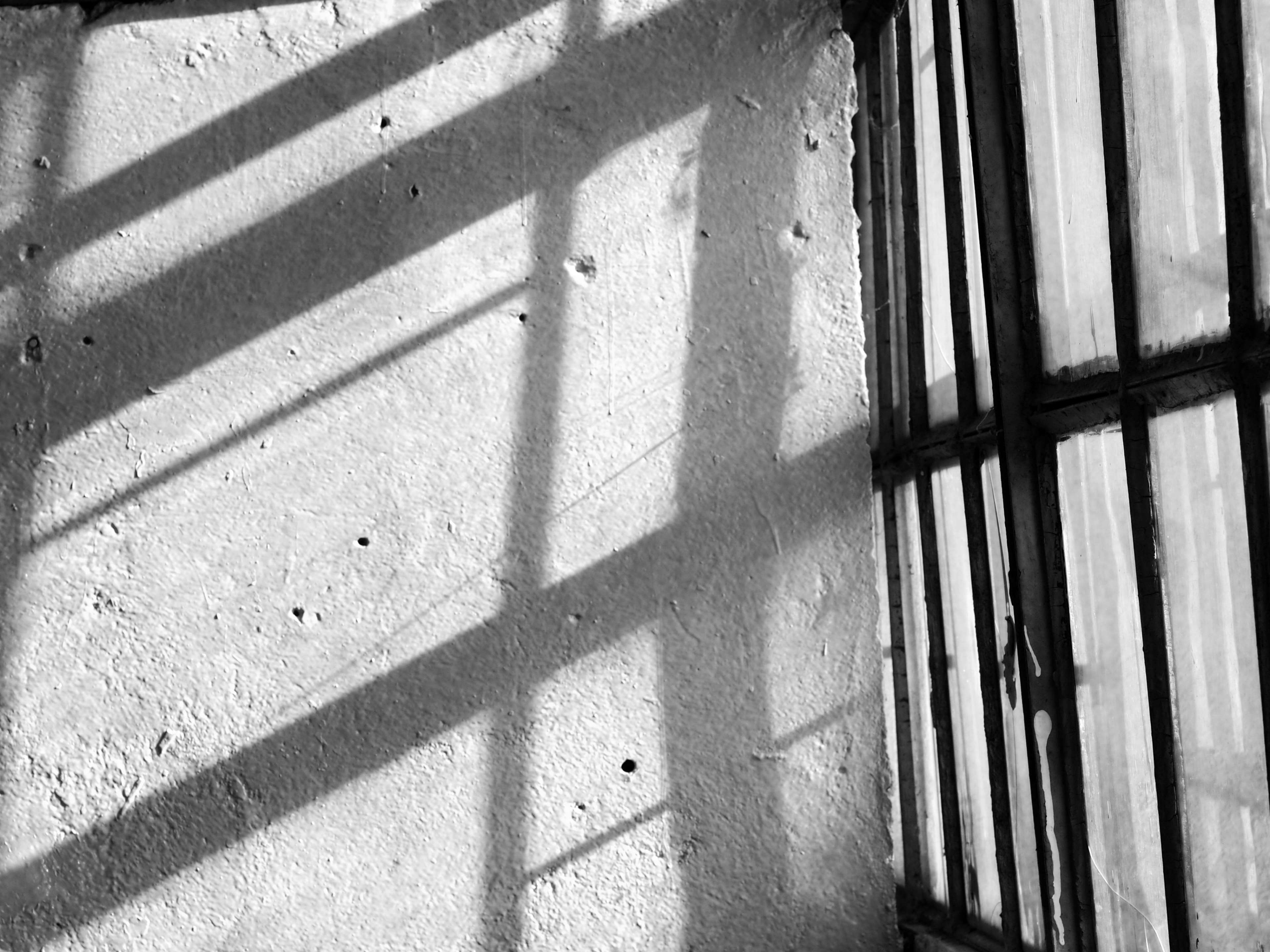 Shadows on a textured wall near a barred window HD Wallpaper